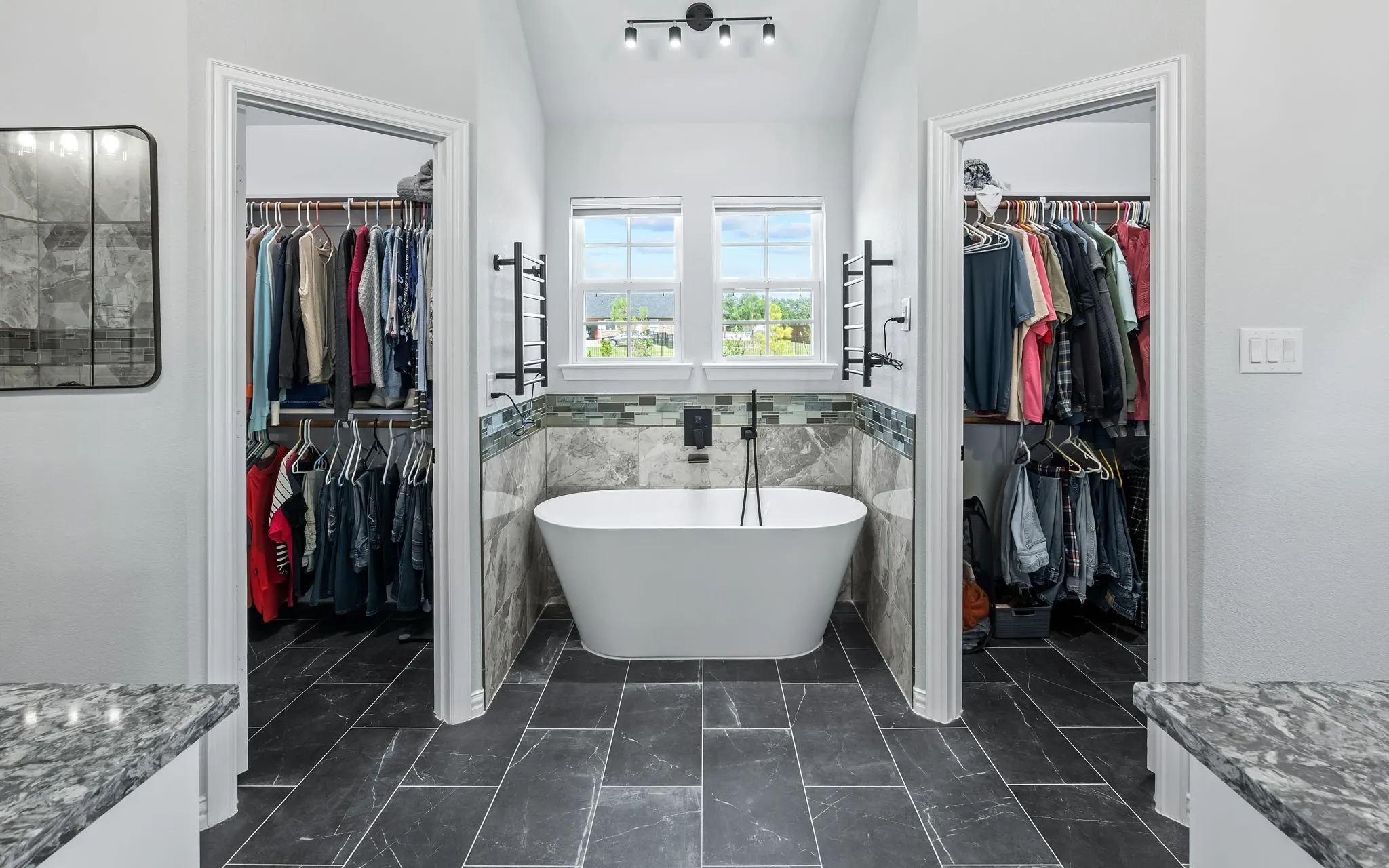 Freestanding soaking tub with a floor-mounted faucet, flanked by two walk-in closets