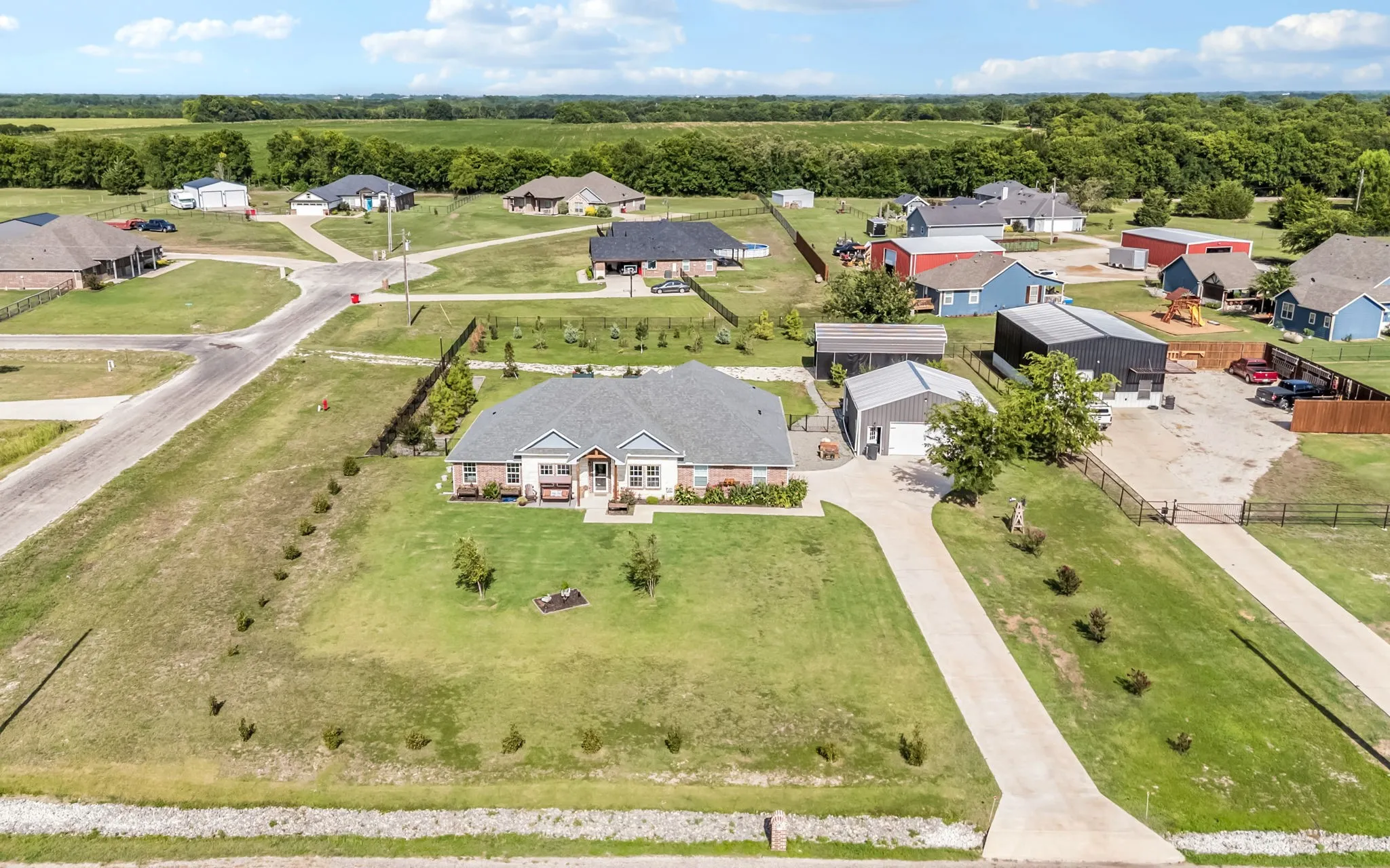 Expansive property with a one story, a detached workshop, concrete driveways, covered RV parking and a wrought iron fenced backyard with a tree lined perimeter on an ACRE corner lot