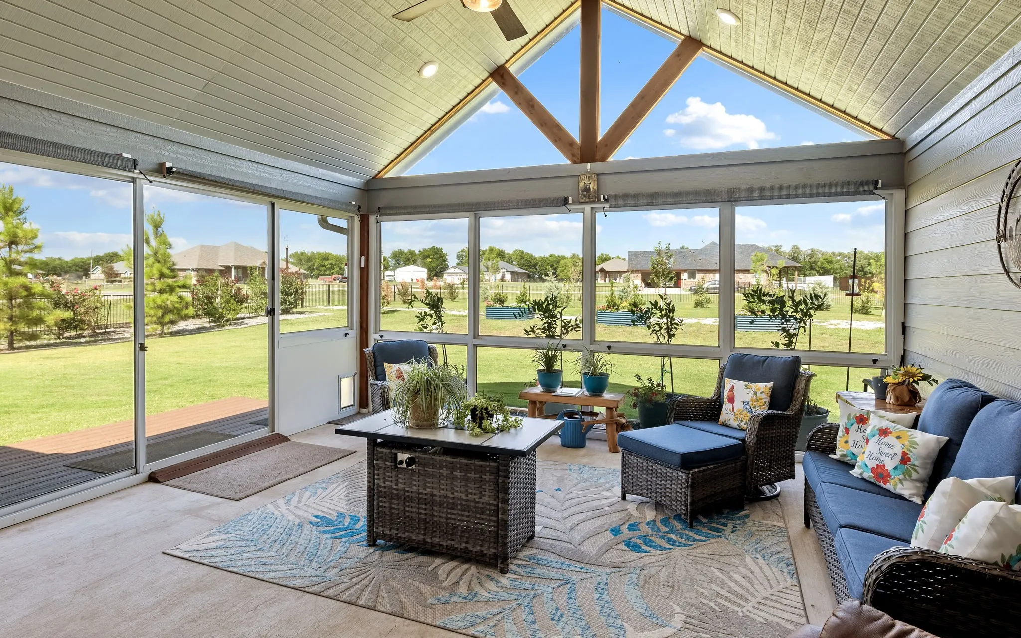 Enclosed patio featuring a vaulted ceiling with exposed wood beams, full-height screened windows, a glass sliding door, and integrated ceiling lighting
