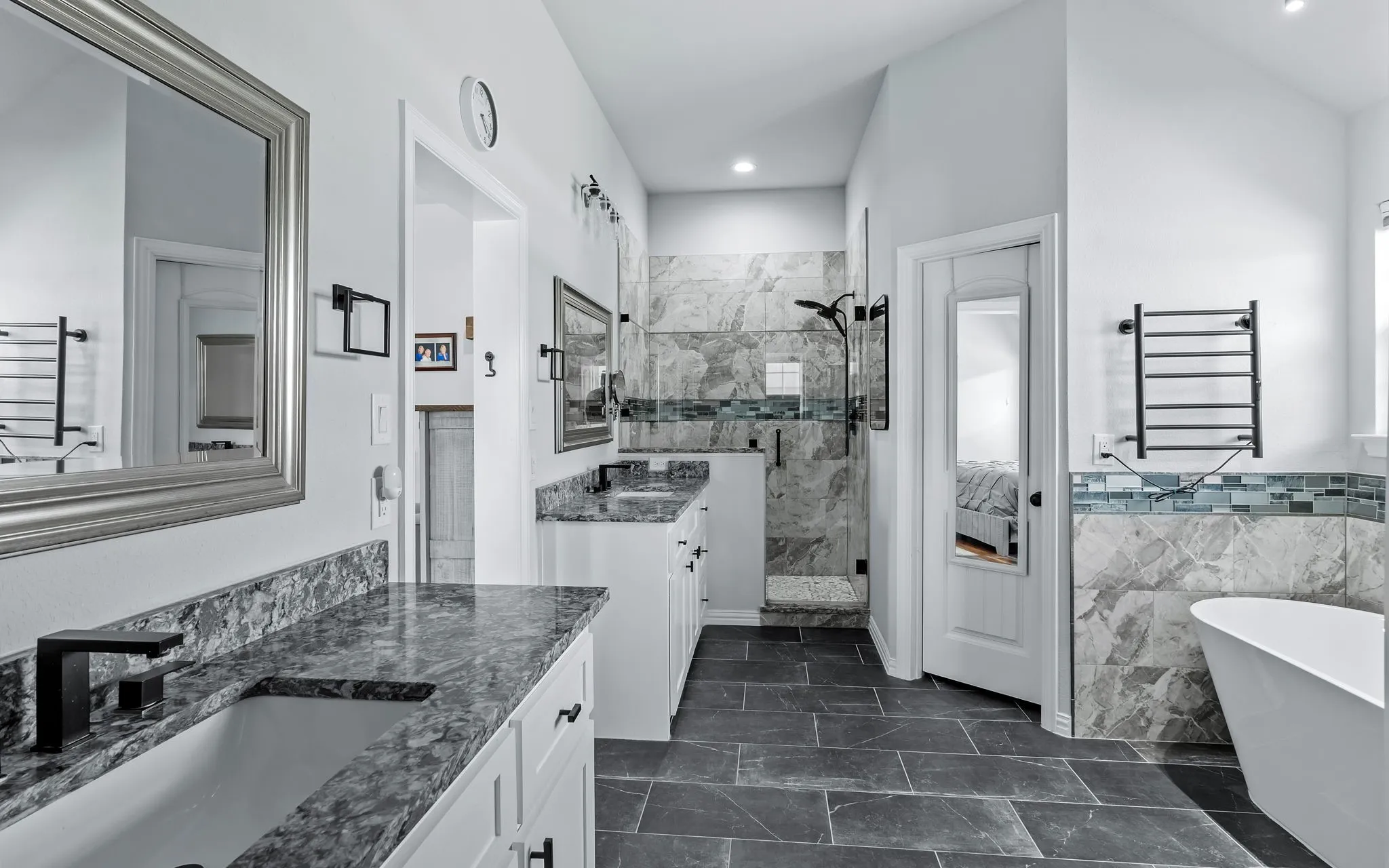Bathroom featuring dual vanities and a tiled shower enclosure