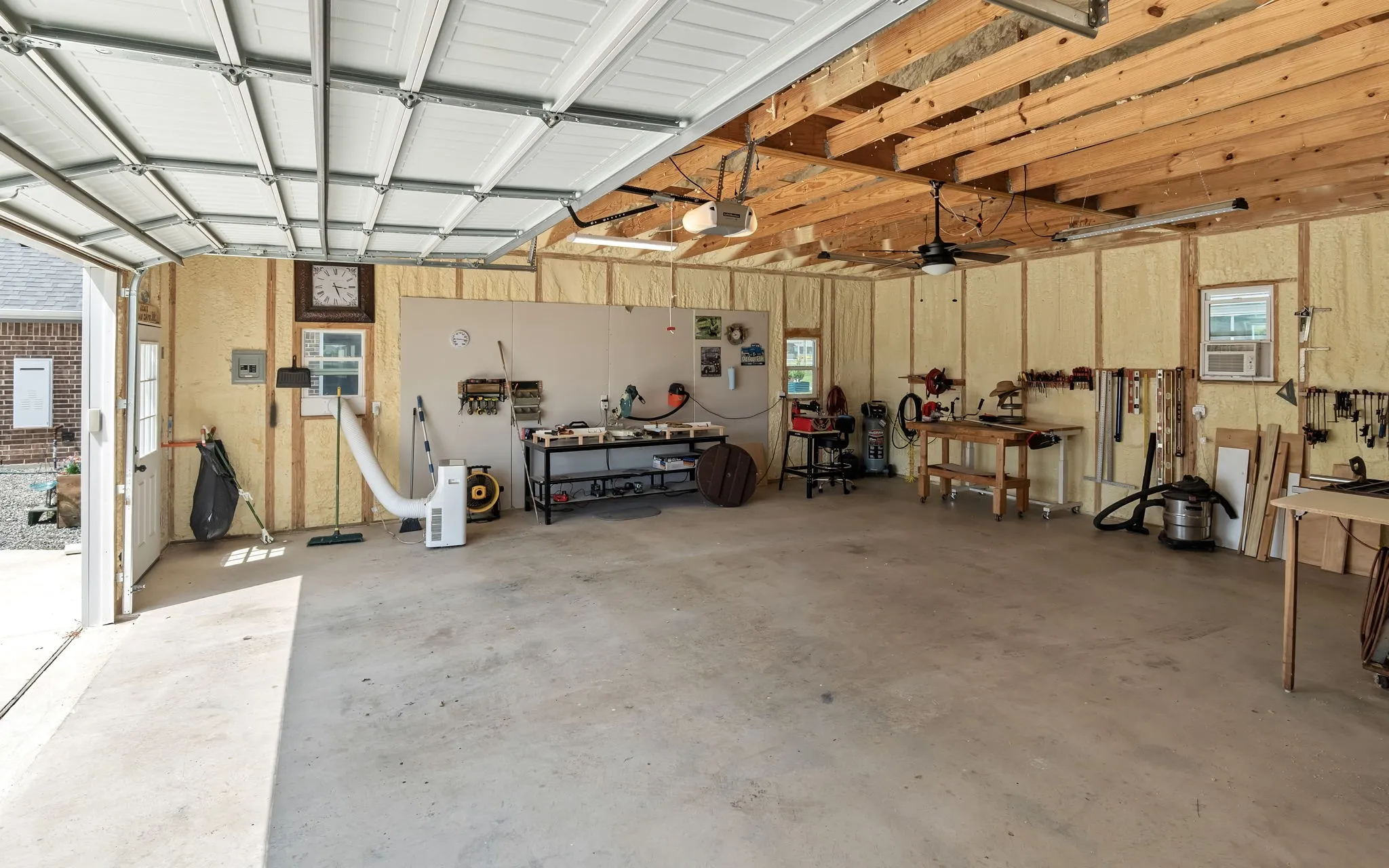 Spacious garage featuring a concrete floor, exposed wood beam ceiling, and insulated walls