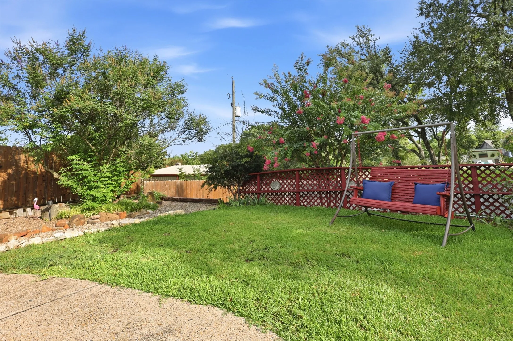 Expansive backyard featuring a lush lawn, mature trees, and a decorative lattice fence