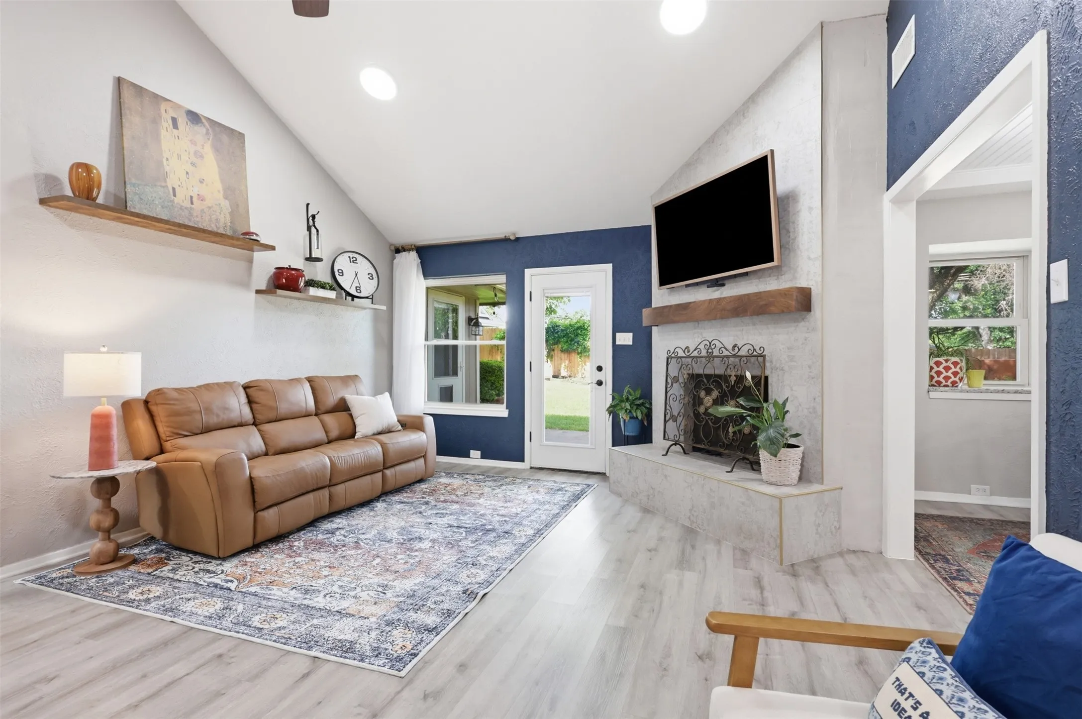 Vaulted ceilings accent this living space featuring light wood-finish flooring