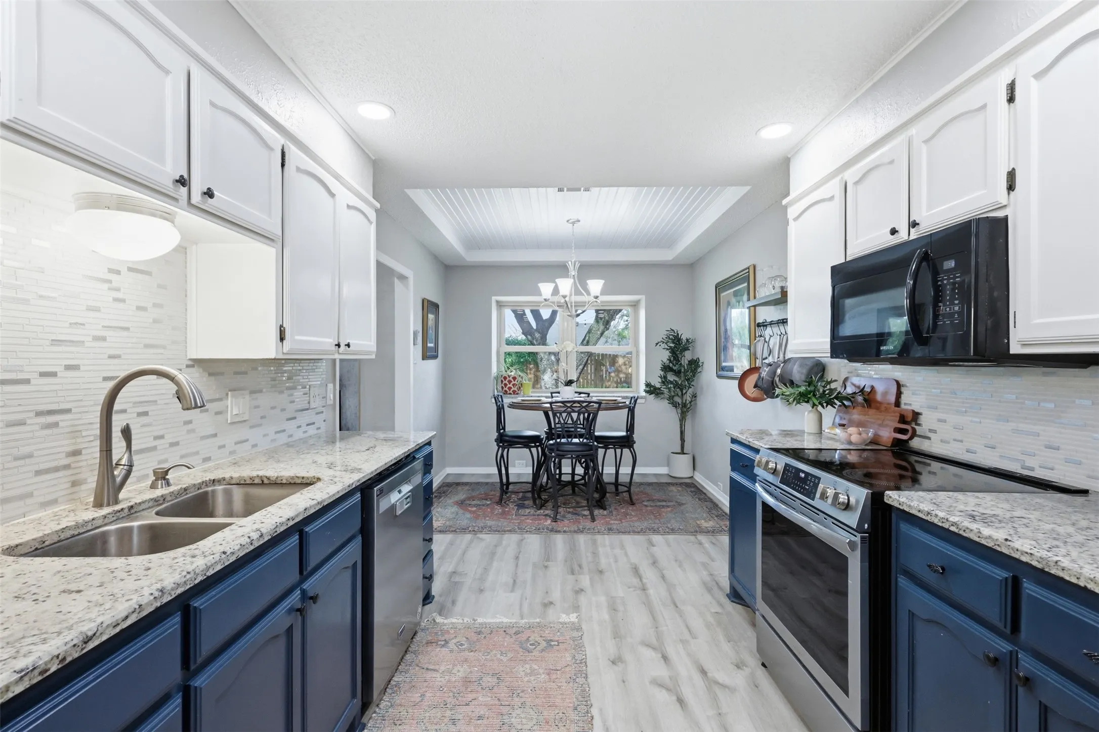 Contemporary kitchen featuring two-tone cabinetry, light-toned countertops, and a full tile backsplash
