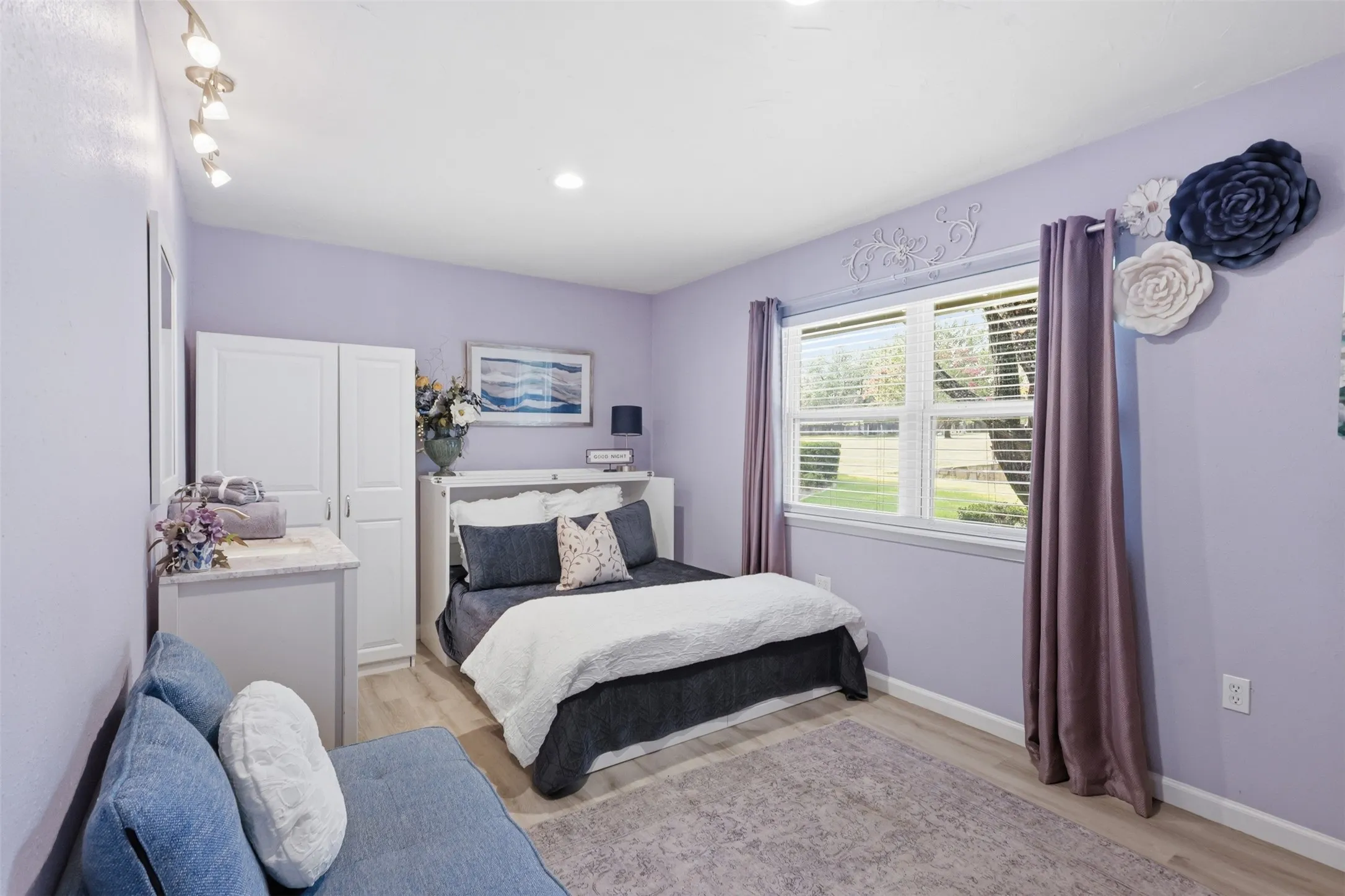 Bright interior space featuring a double window with blinds, light wood-finish flooring, recessed lighting, and track lighting