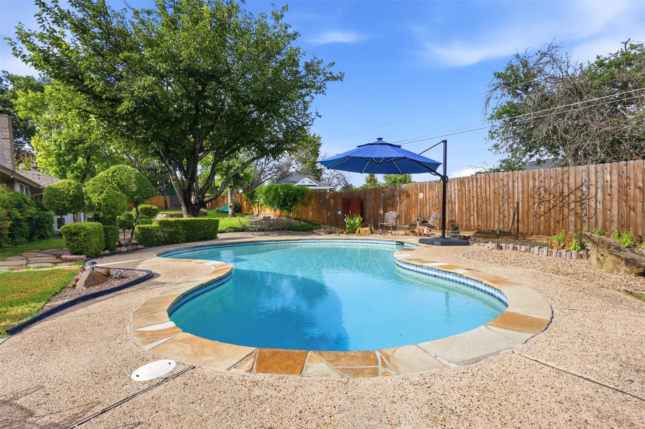 Curved swimming pool with stone coping and concrete decking