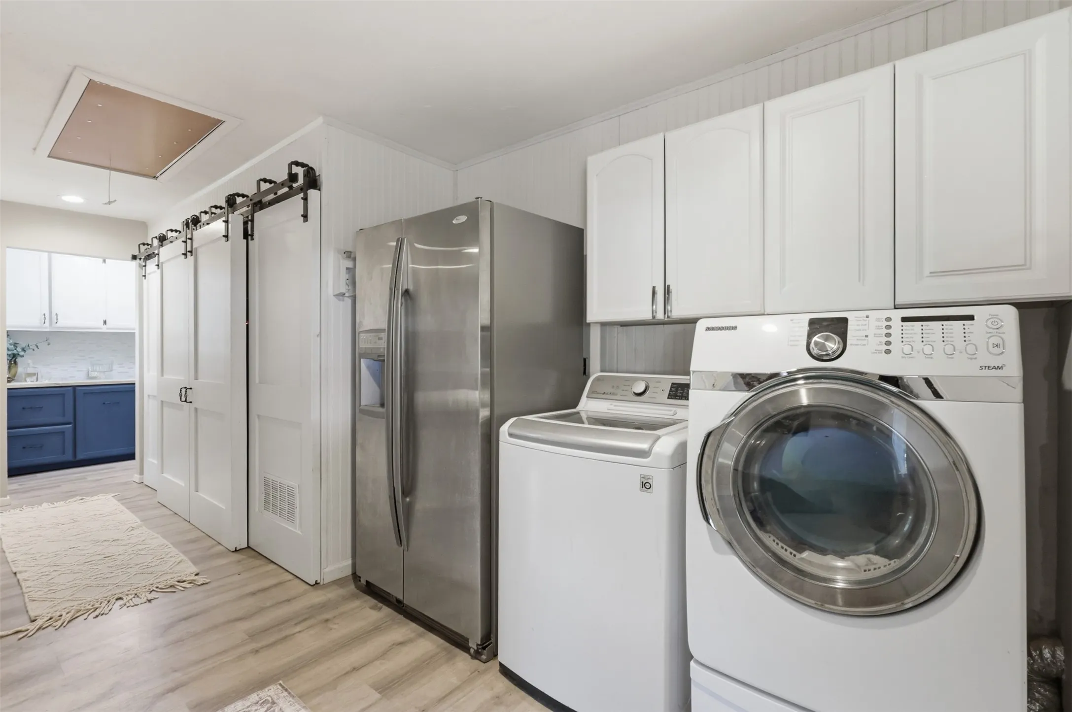 Dedicated utility space featuring a front-load washing machine, stacked dryer, and overhead white cabinetry