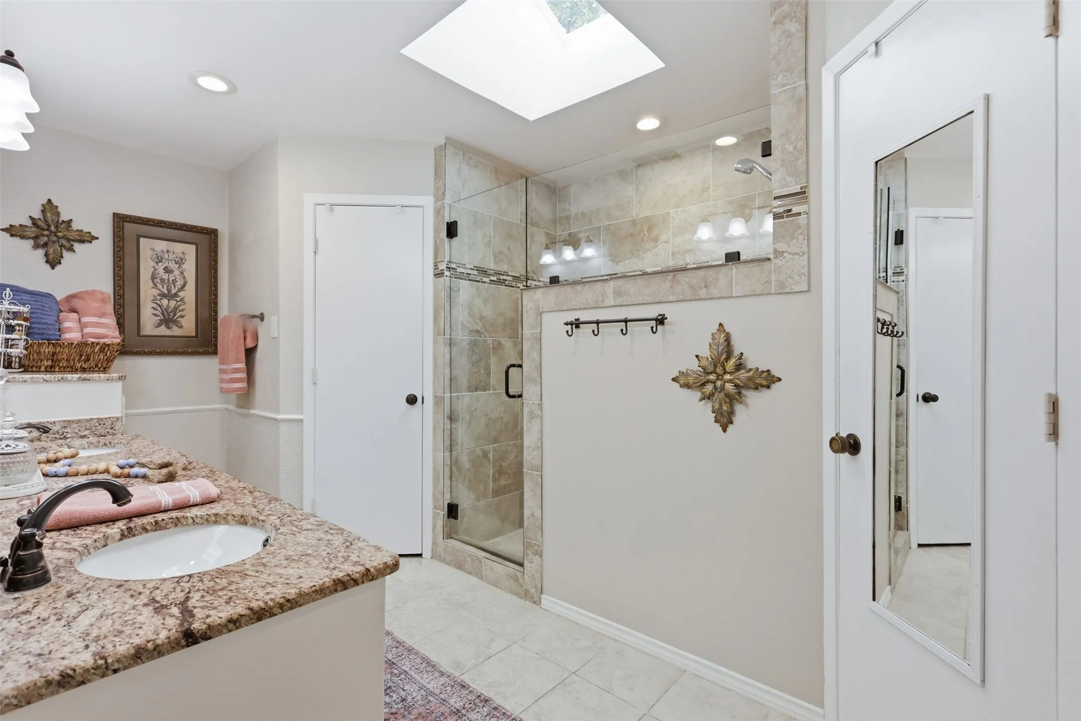 Bathroom featuring a granite vanity with an undermount sink, a glass-enclosed shower with tiled walls, a skylight, and recessed lighting