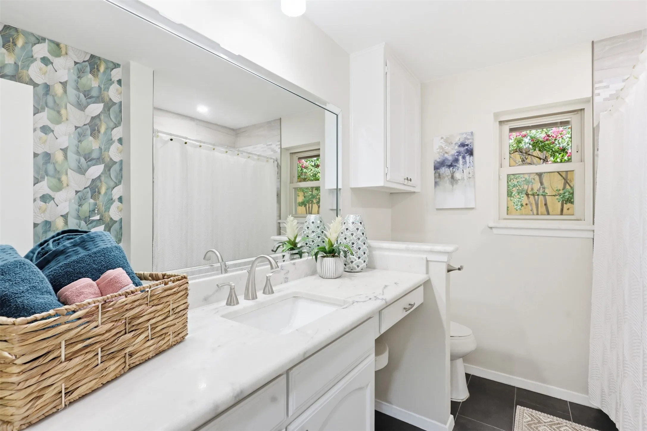 Bathroom featuring a wide vanity with a rectangular undermount sink, a large mirror, white cabinetry, a window, and a shower with a white curtain