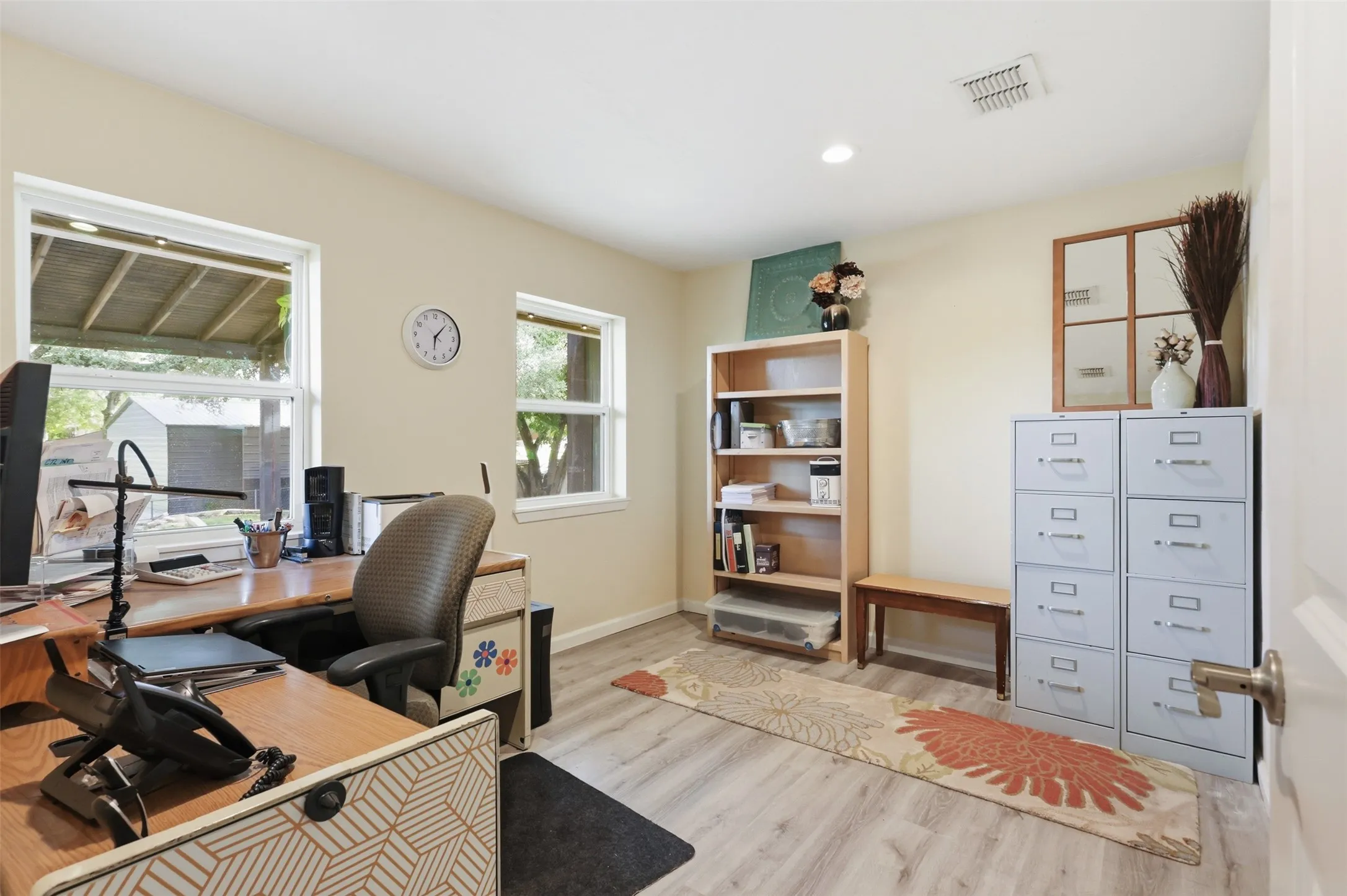 Light-filled room featuring wood-finish flooring, two windows, recessed lighting, and a built-in ceiling vent