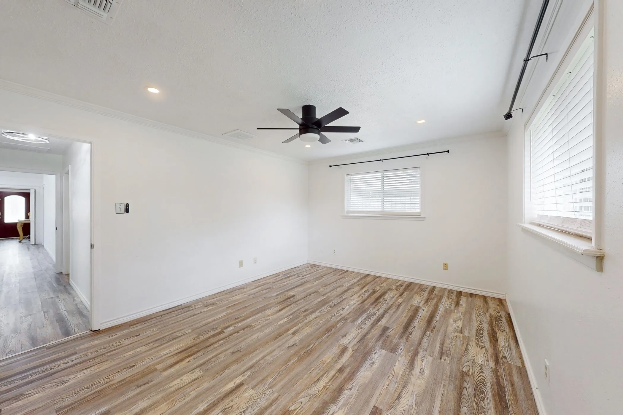 Spacious room with wood-finish flooring, recessed lighting, and a contemporary ceiling fan