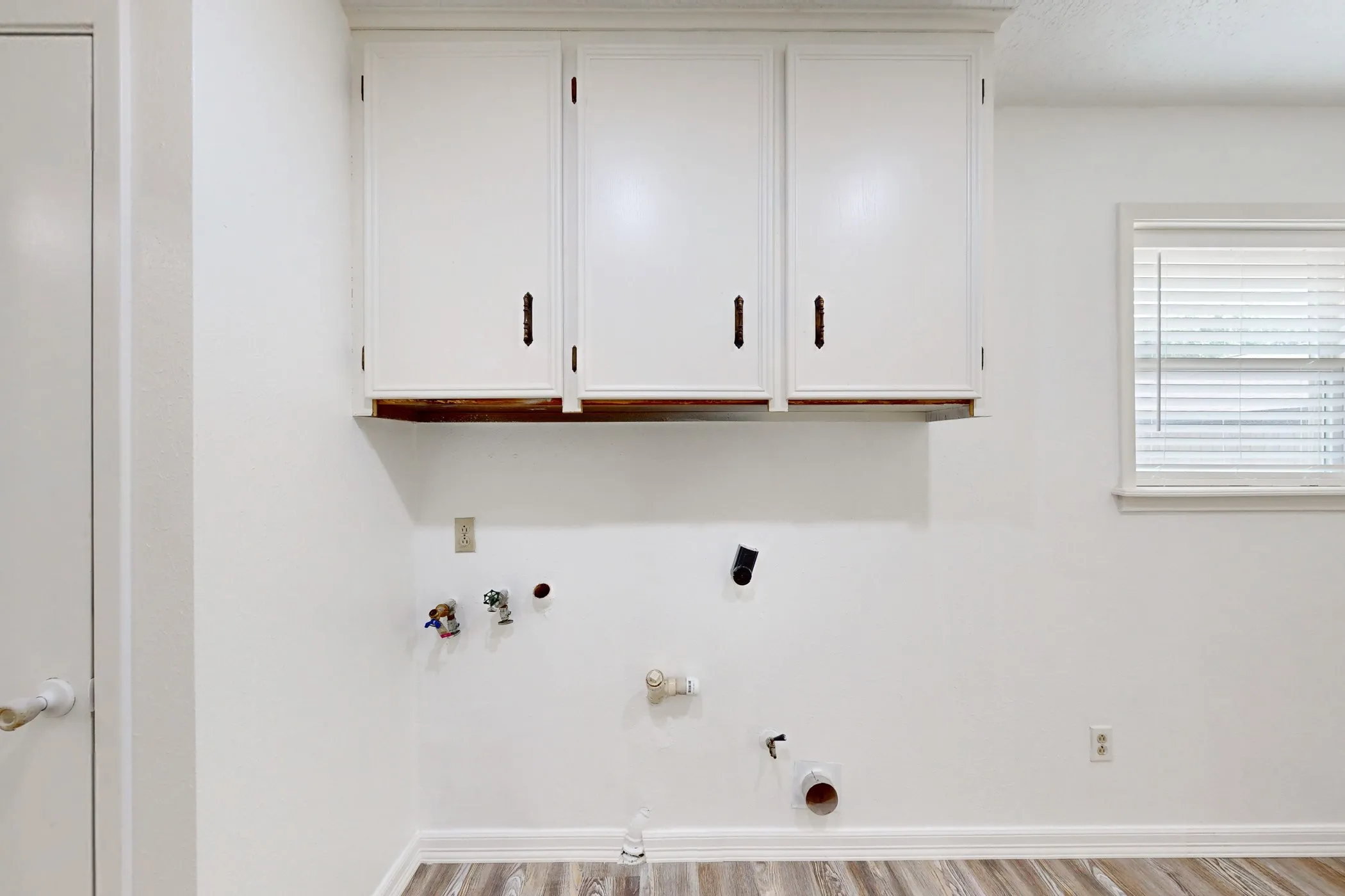 White upper cabinetry with dark hardware and a wood-finish shelf