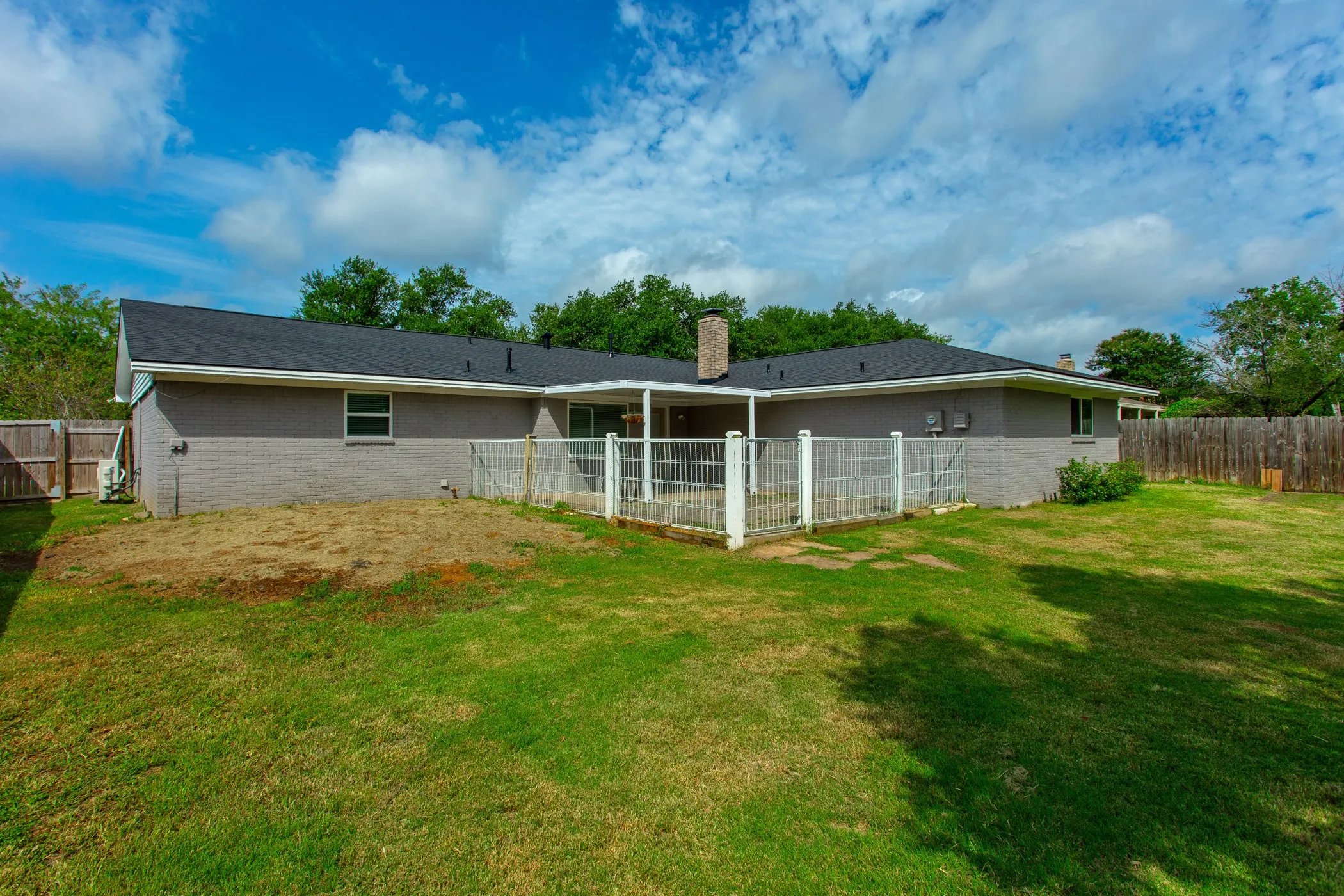 Spacious backyard featuring a covered patio, fenced area, and mature perimeter fencing