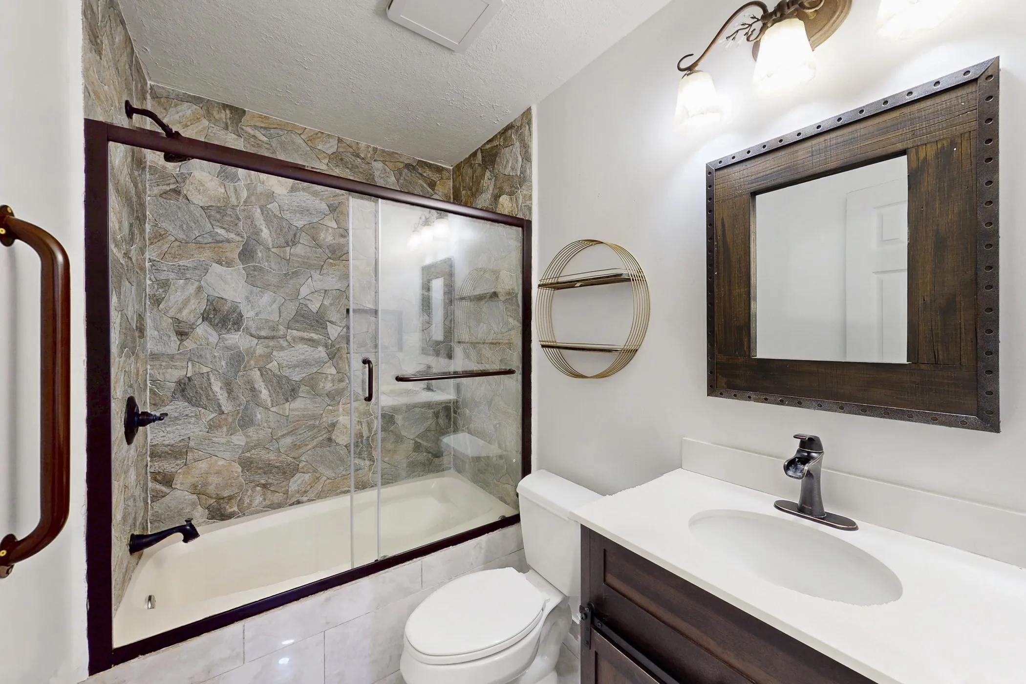 Bathroom featuring a tub/shower combination with stone-look tile surround and sliding glass doors
