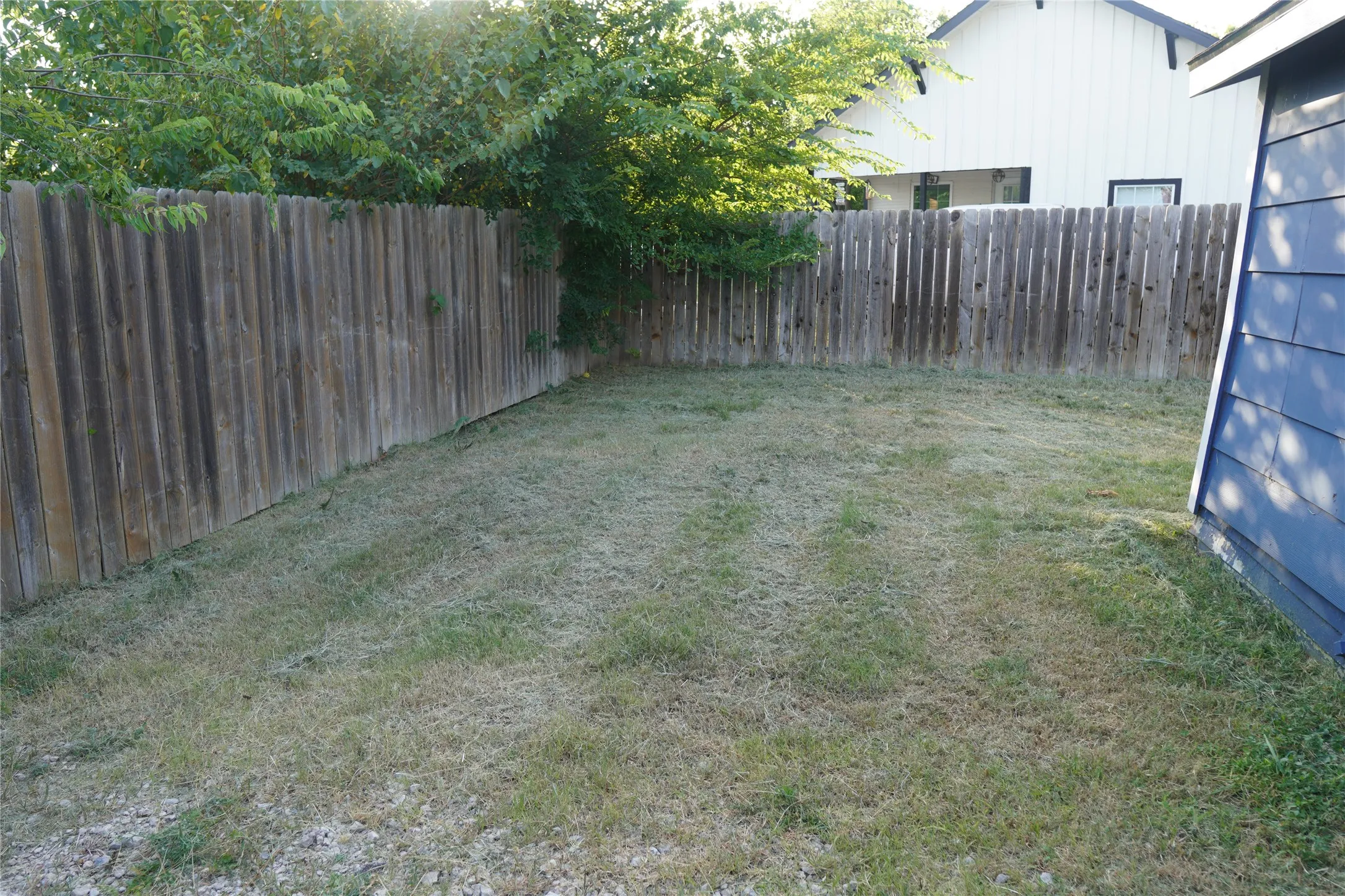 Expansive fenced yard featuring natural wood privacy fencing and a grass lawn