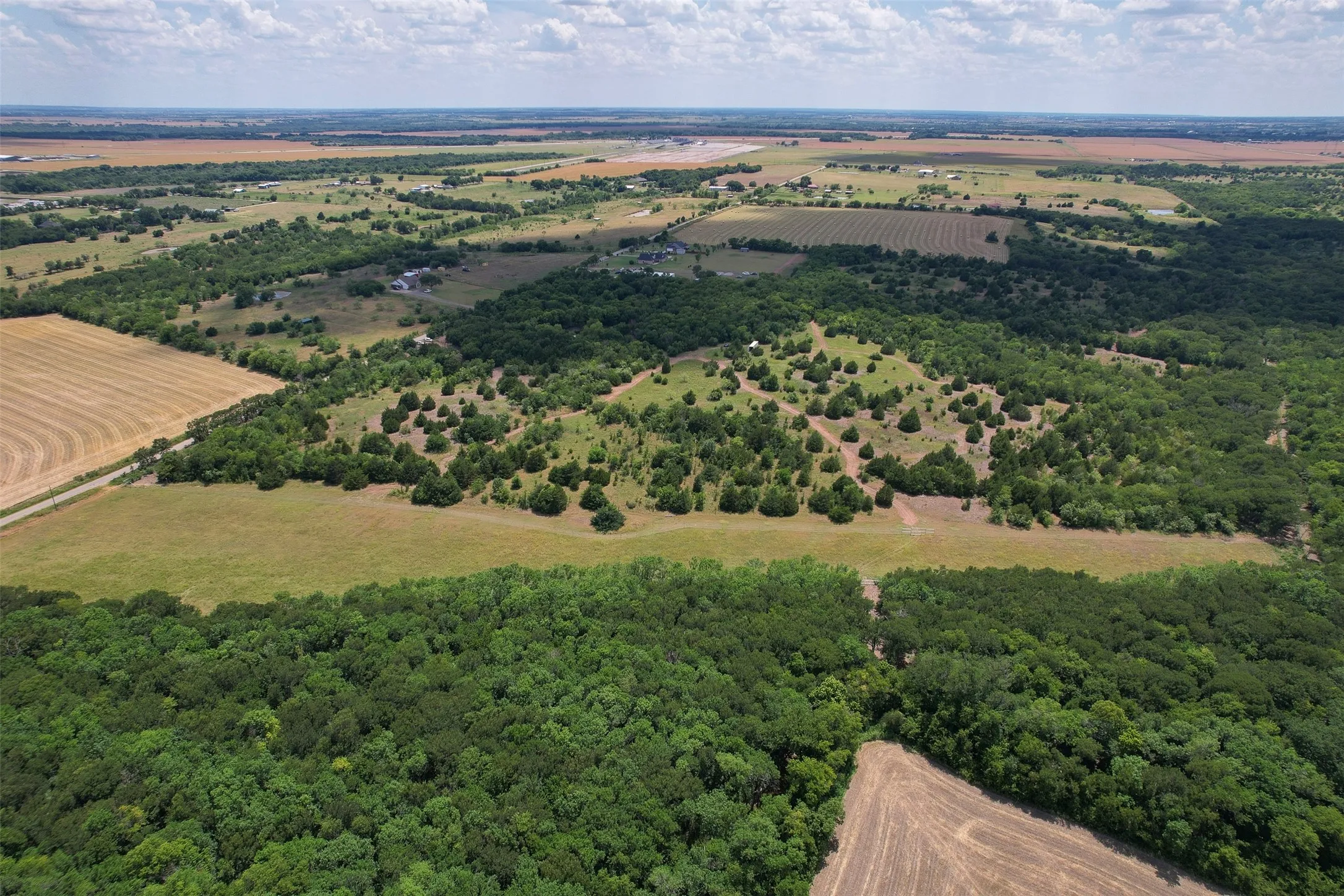 Expansive aerial landscape featuring a mix of dense woodland, open fields, and cultivated land