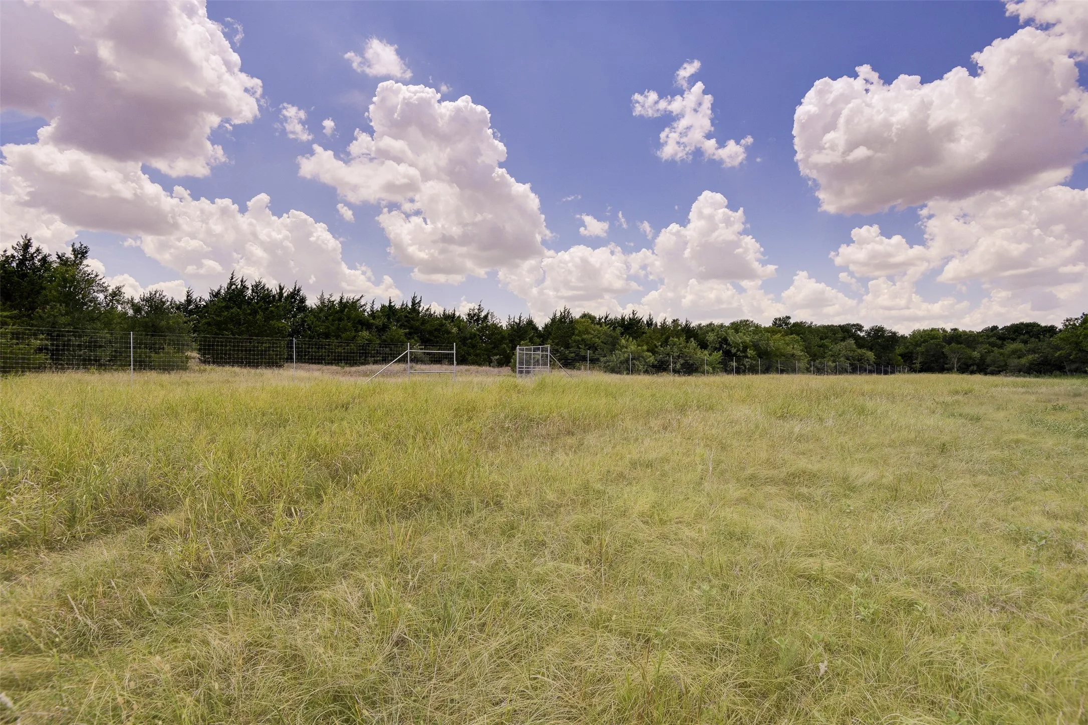 Expansive open field featuring hay and perimeter fencing