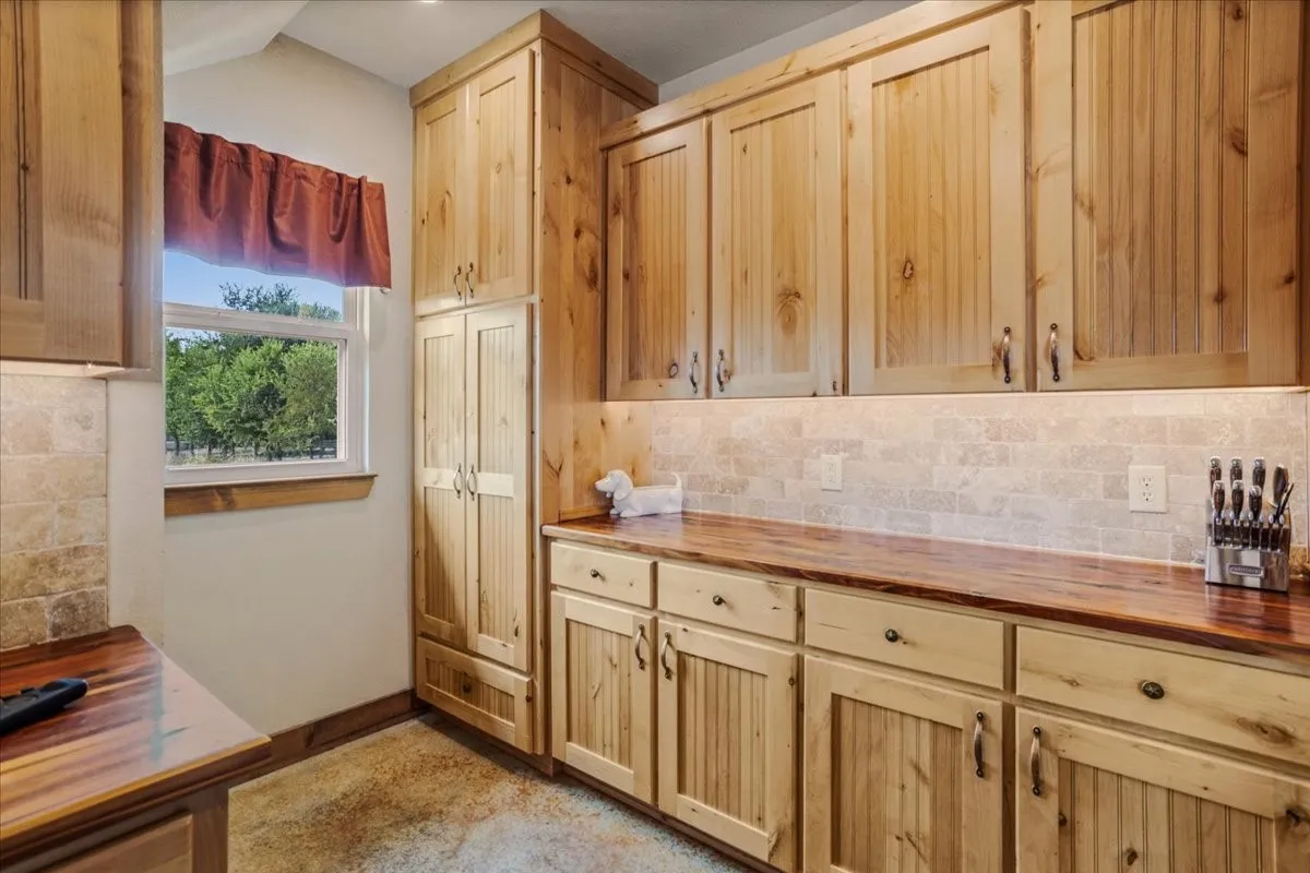 Kitchen featuring extensive natural wood cabinetry, wood-finish countertops, and a tiled backsplash