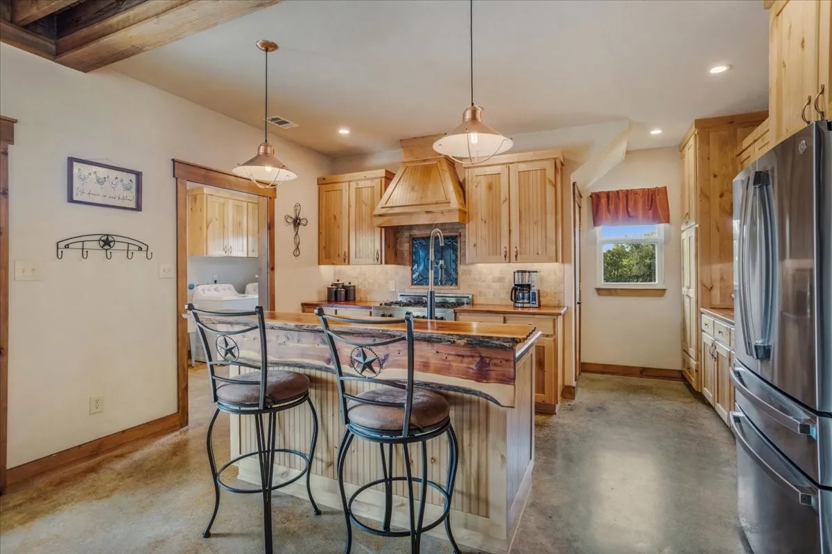 Kitchen featuring a rustic wood ceiling, light wood cabinetry, a central island with a wood-finish countertop, and stainless steel appliances