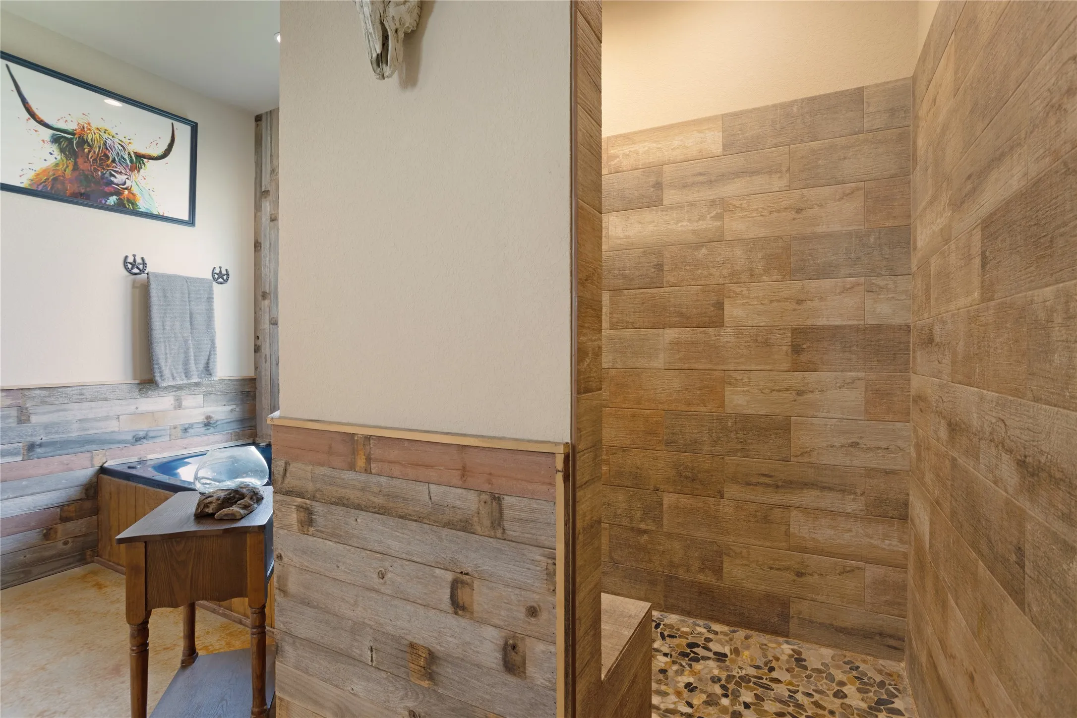 Walk-in shower featuring wood-look tile walls and a pebble-stone floor