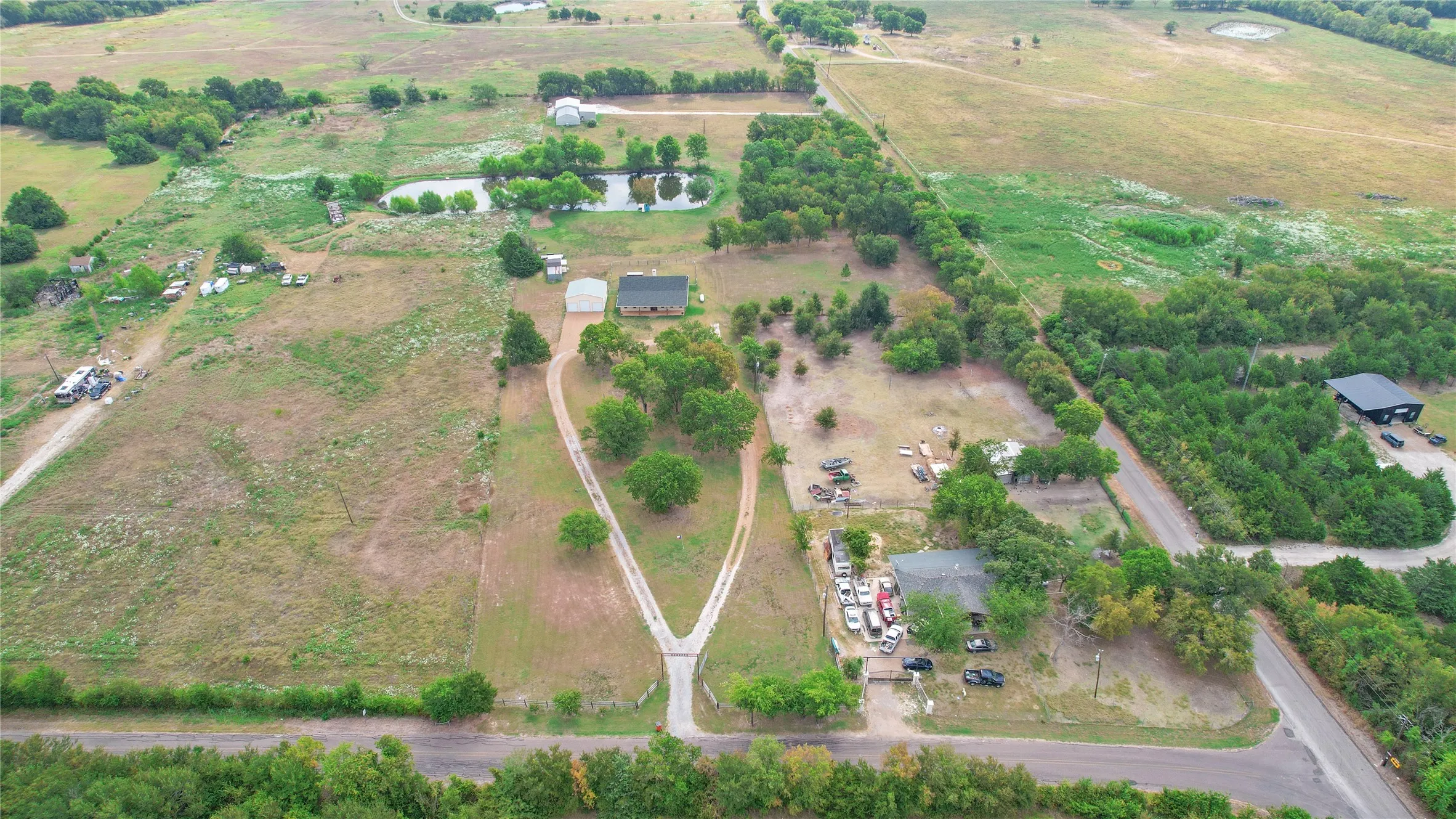 Expansive rural property featuring multiple structures, a Y-shaped driveway, and two ponds