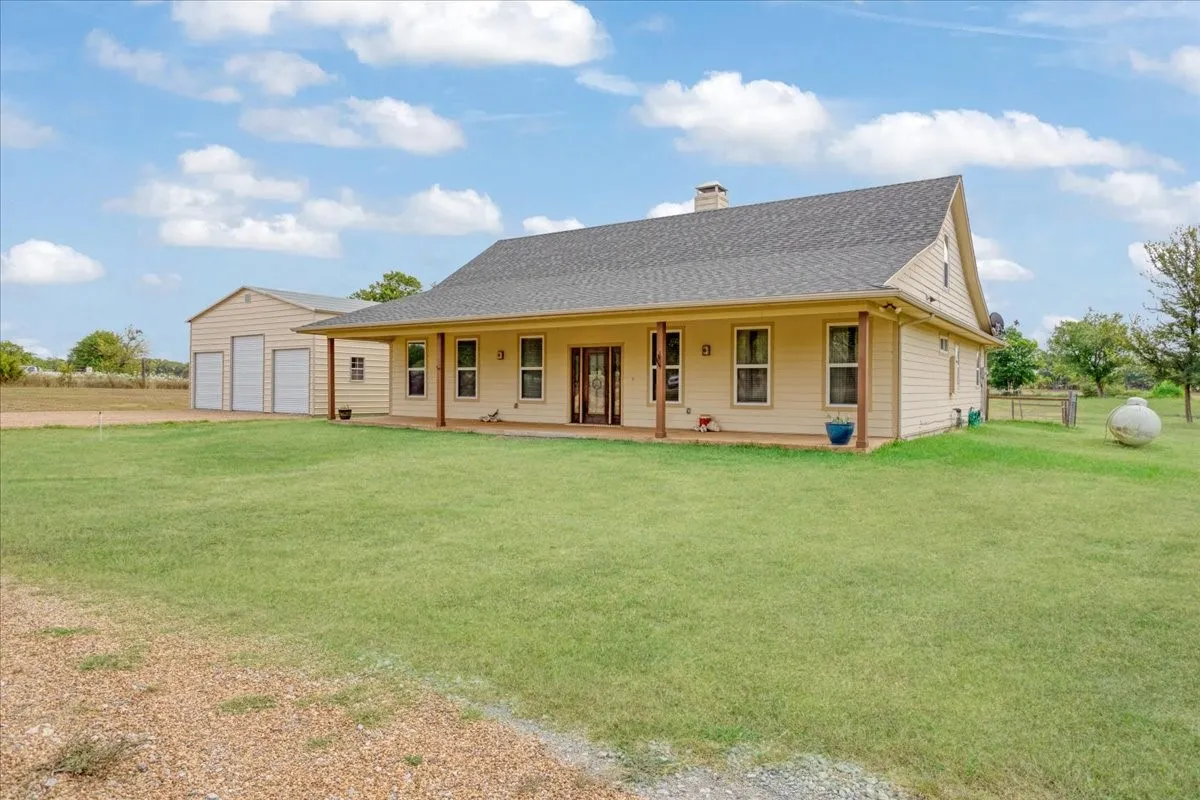 Ranch-style residence featuring a covered front porch, light-colored siding, and a dark shingle roof