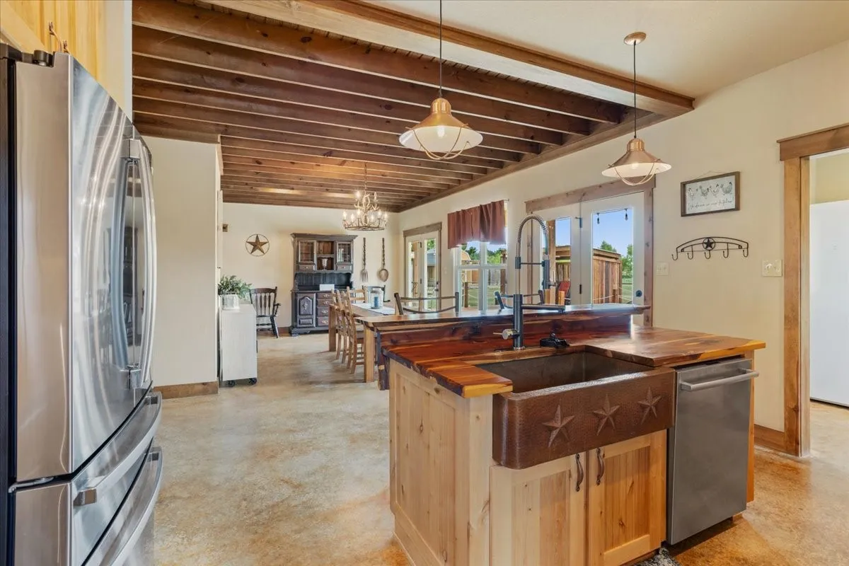 Kitchen island featuring a copper farmhouse sink with star detailing, wood countertops, and a stainless steel dishwasher
