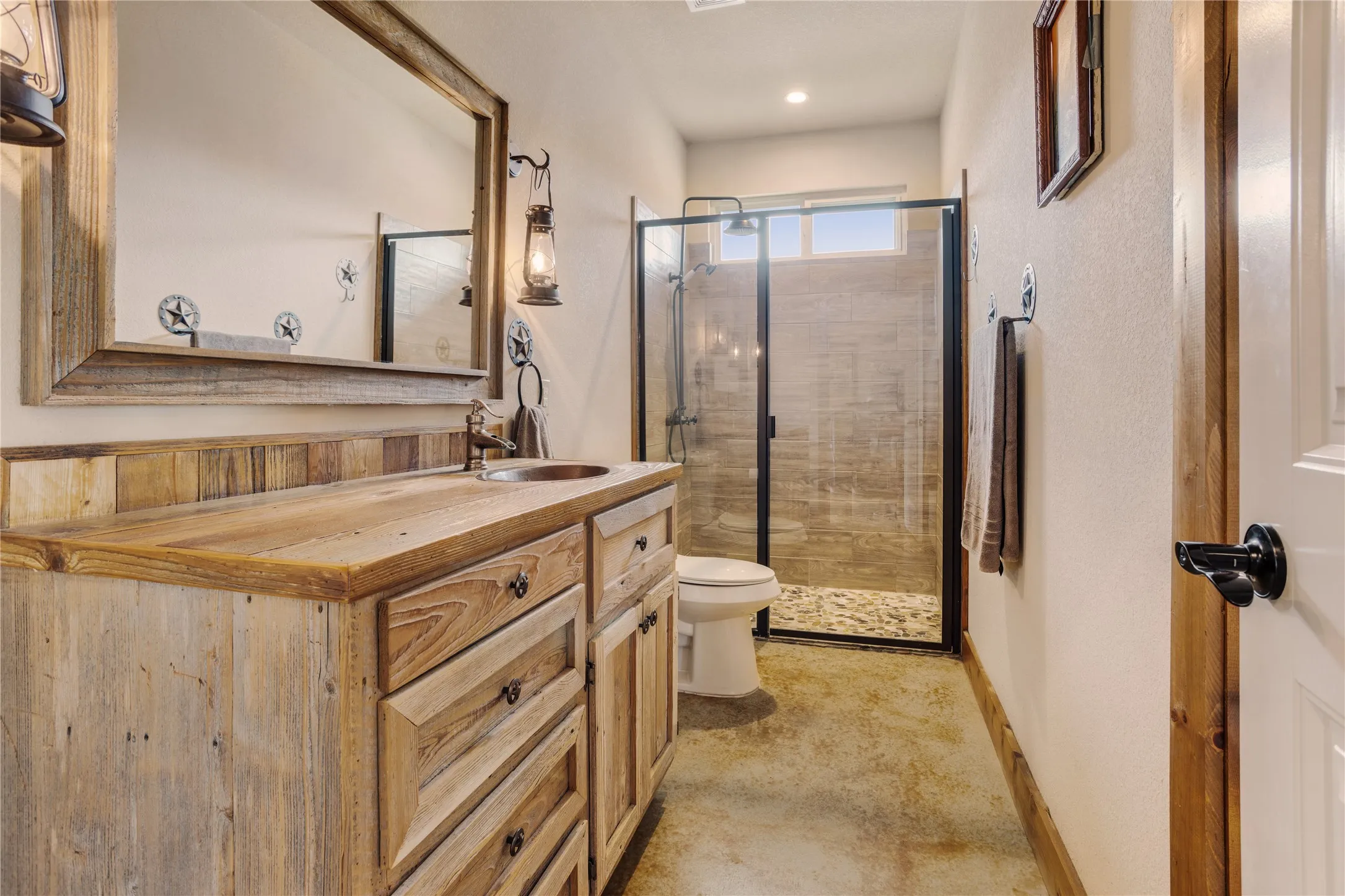 Rustic wood-finish vanity with an integrated sink, framed mirror, and lantern-style sconce lighting