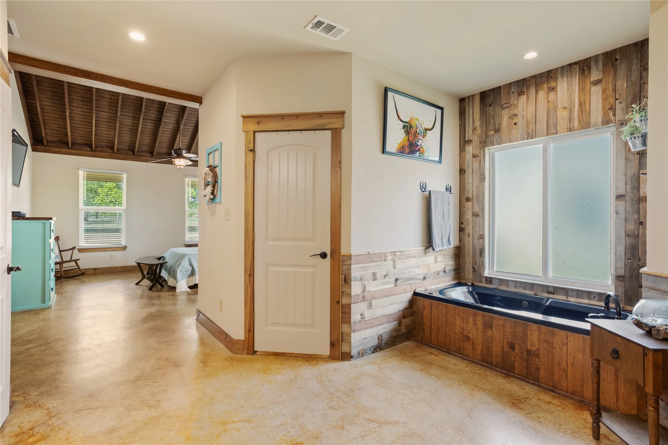 Sleek soaking tub set against a feature wall of horizontal wood paneling and a frosted window