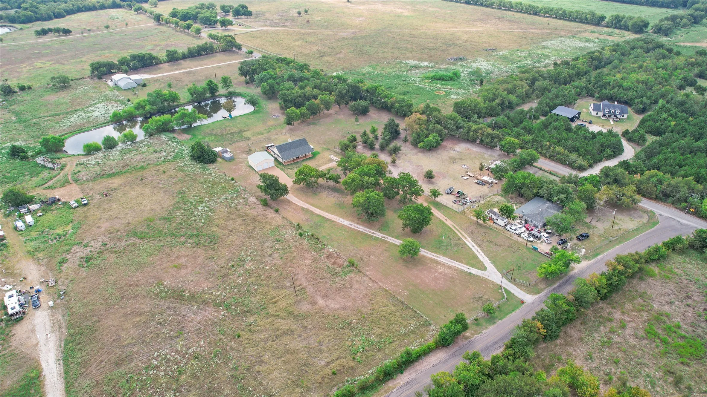 Expansive acreage featuring multiple structures, a pond, and mature tree lines
