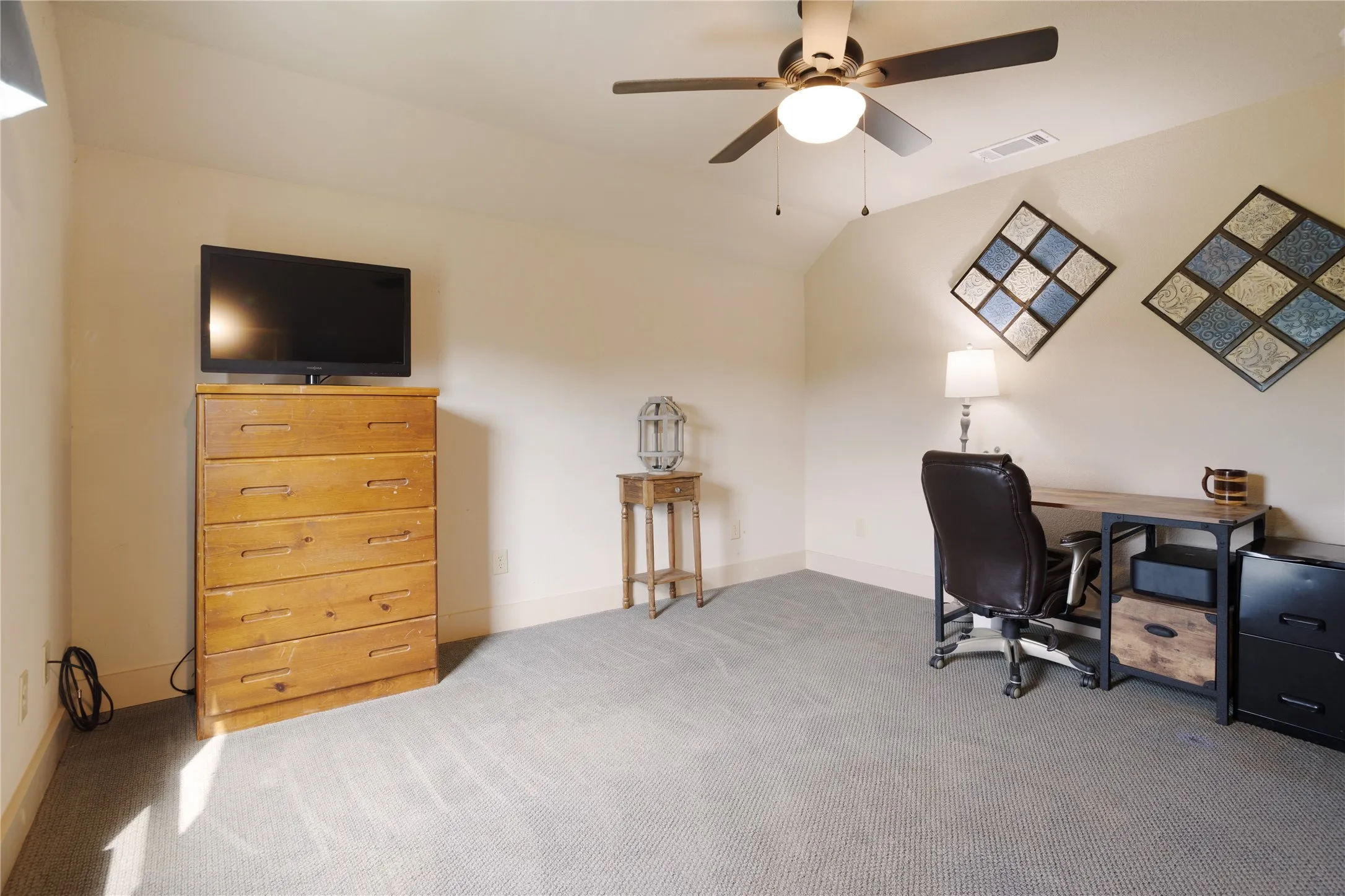Carpeted room with a vaulted ceiling and a ceiling fan with integrated lighting