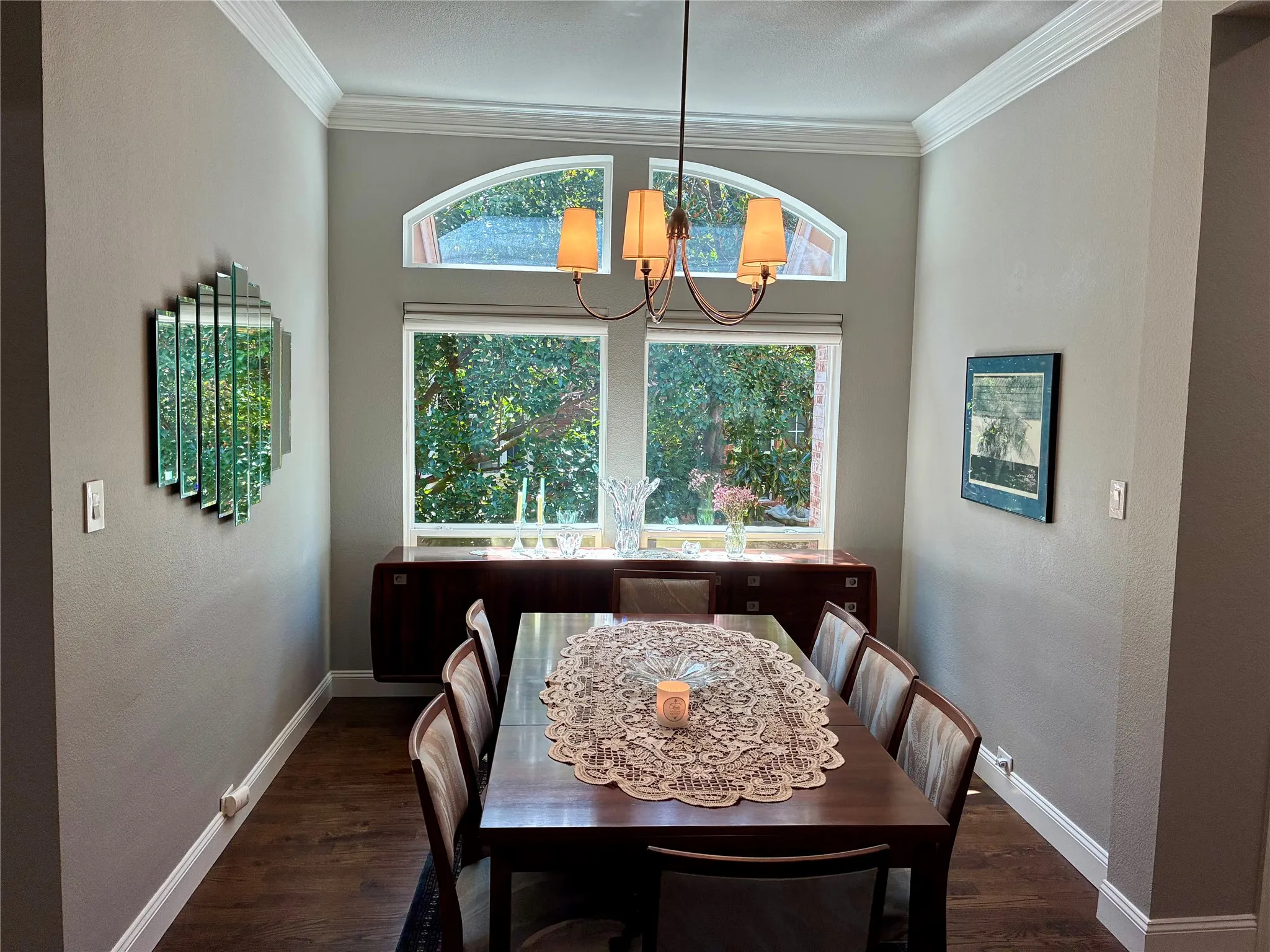 Dining area featuring wood-finish flooring, a contemporary chandelier, crown molding, and a built-in credenza