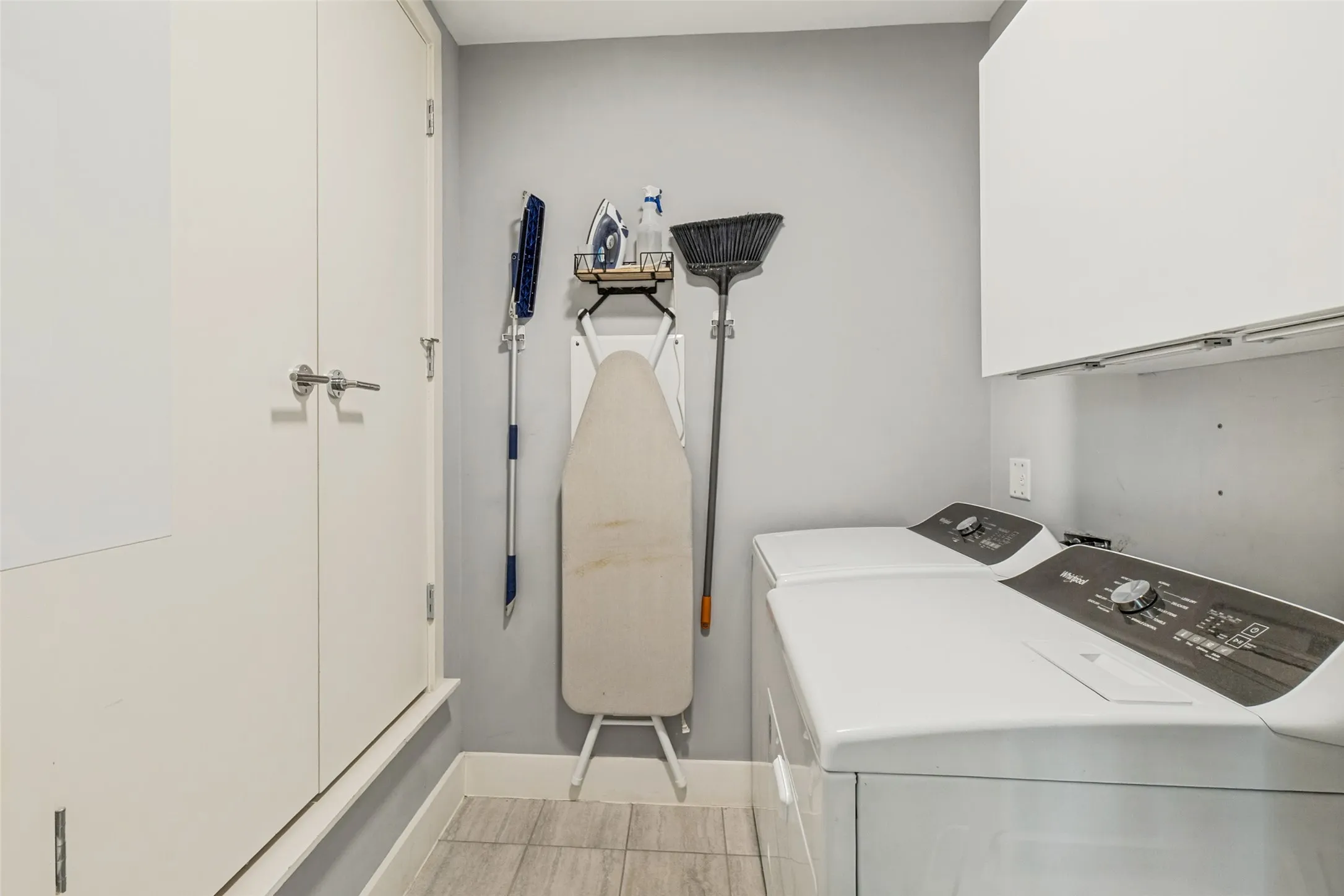 Dedicated laundry area featuring a white washing machine and dryer, overhead cabinetry, and light gray wall paint