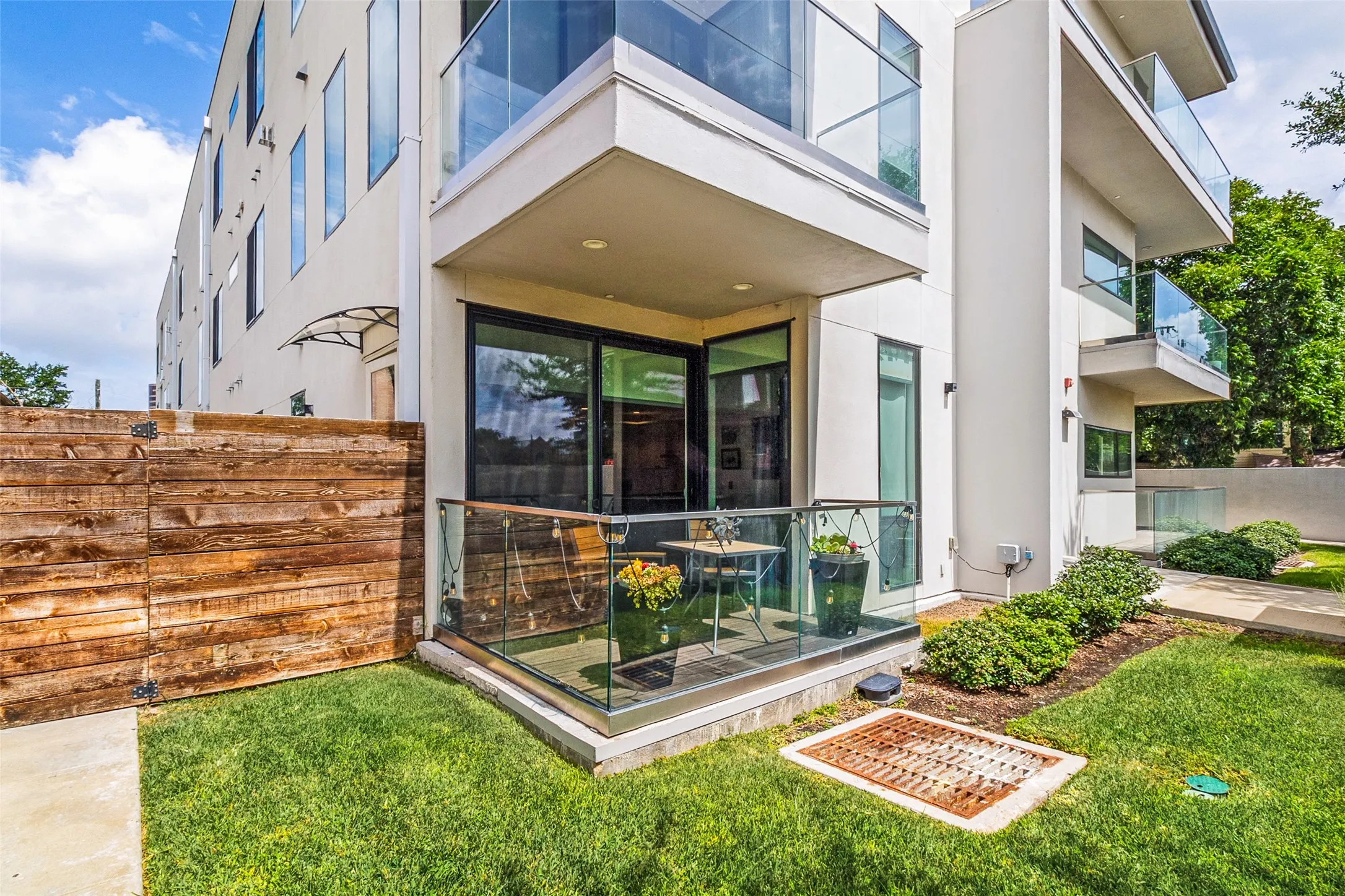 Private ground-level patio with glass railing and fenced yard, offering the perfect space for outdoor dining, relaxing, or entertaining.