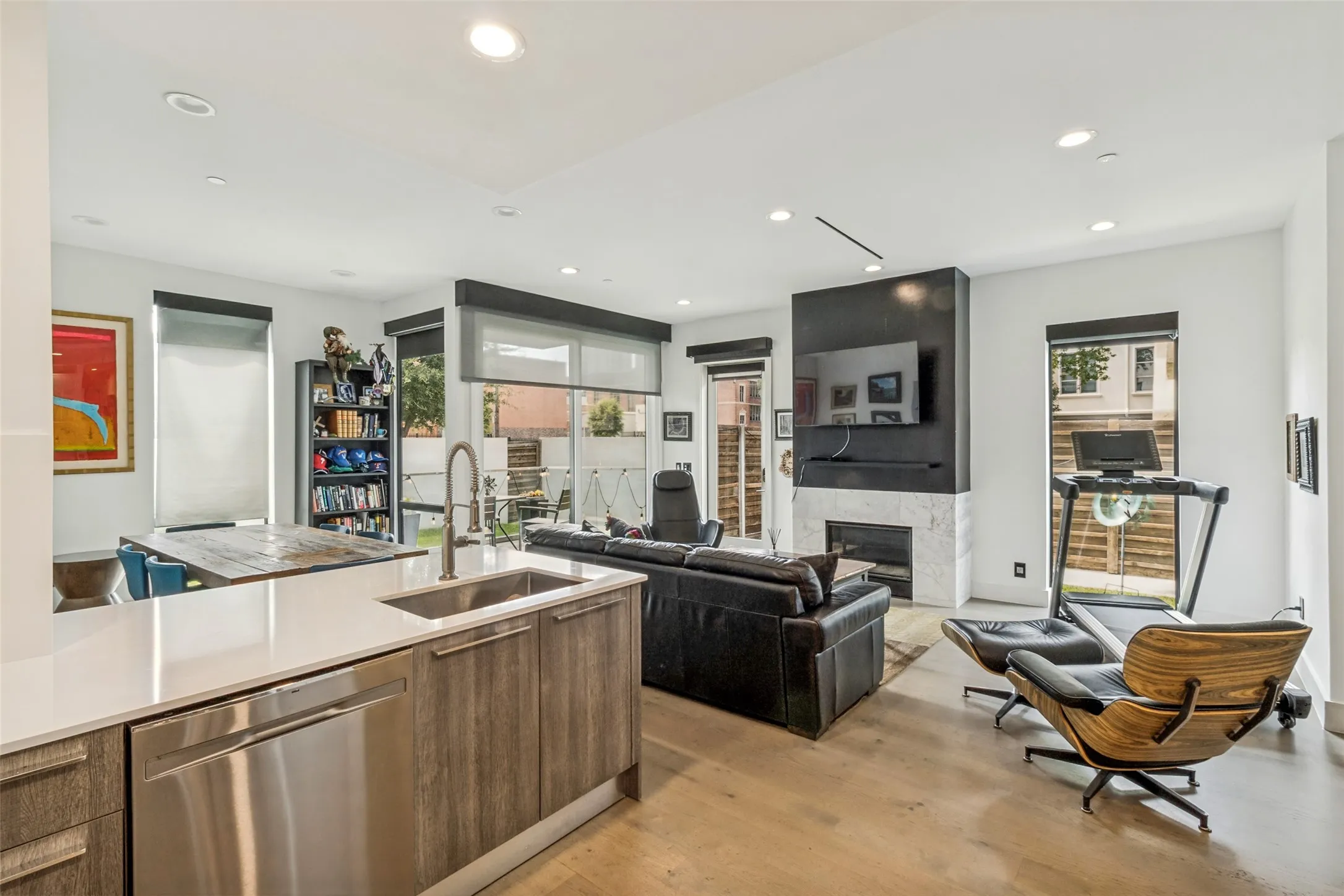 Bright, open-concept living with seamless flow from the kitchen to the living and dining areas, highlighted by expansive windows, a sleek fireplace, and abundant natural light.