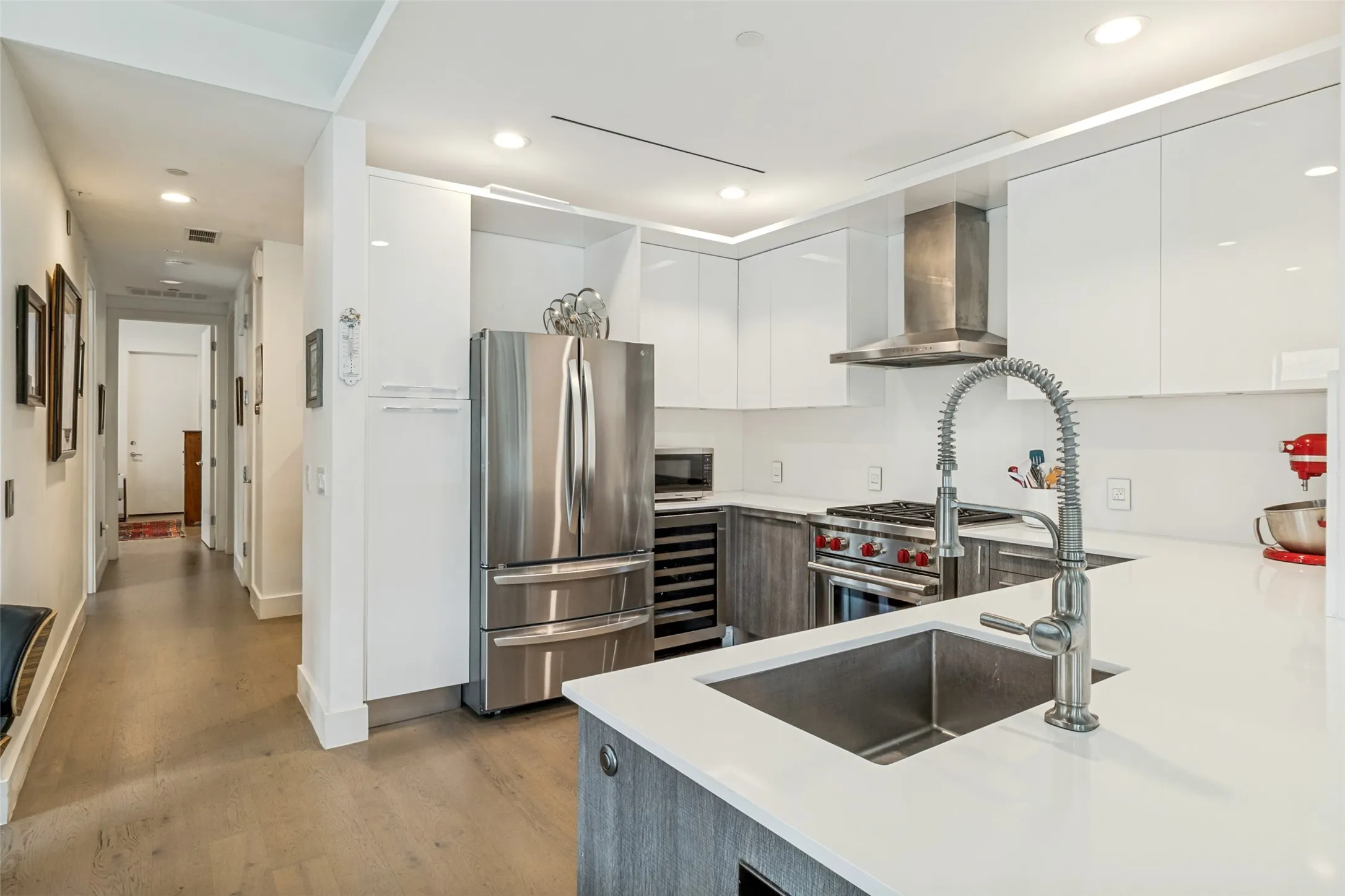 Modern kitchen featuring white flat-panel cabinetry, a stainless steel appliance suite, and light-toned countertops