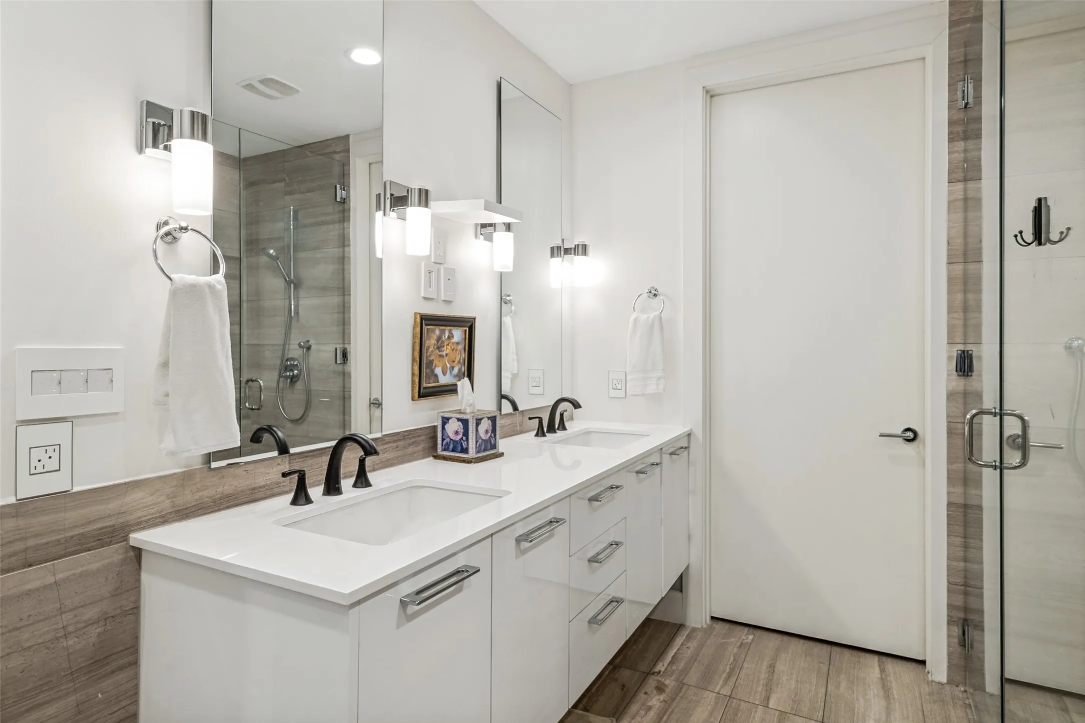 Bathroom featuring a double vanity with white cabinetry and integrated sinks, matte black faucets, and a full-width mirror