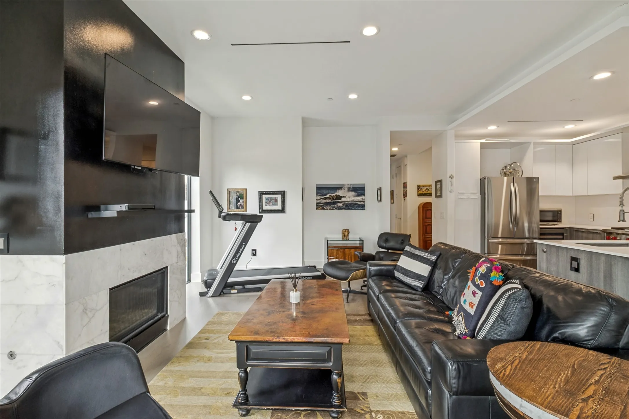 Open-concept living space with a contemporary fireplace featuring a light-colored stone surround and black accent wall