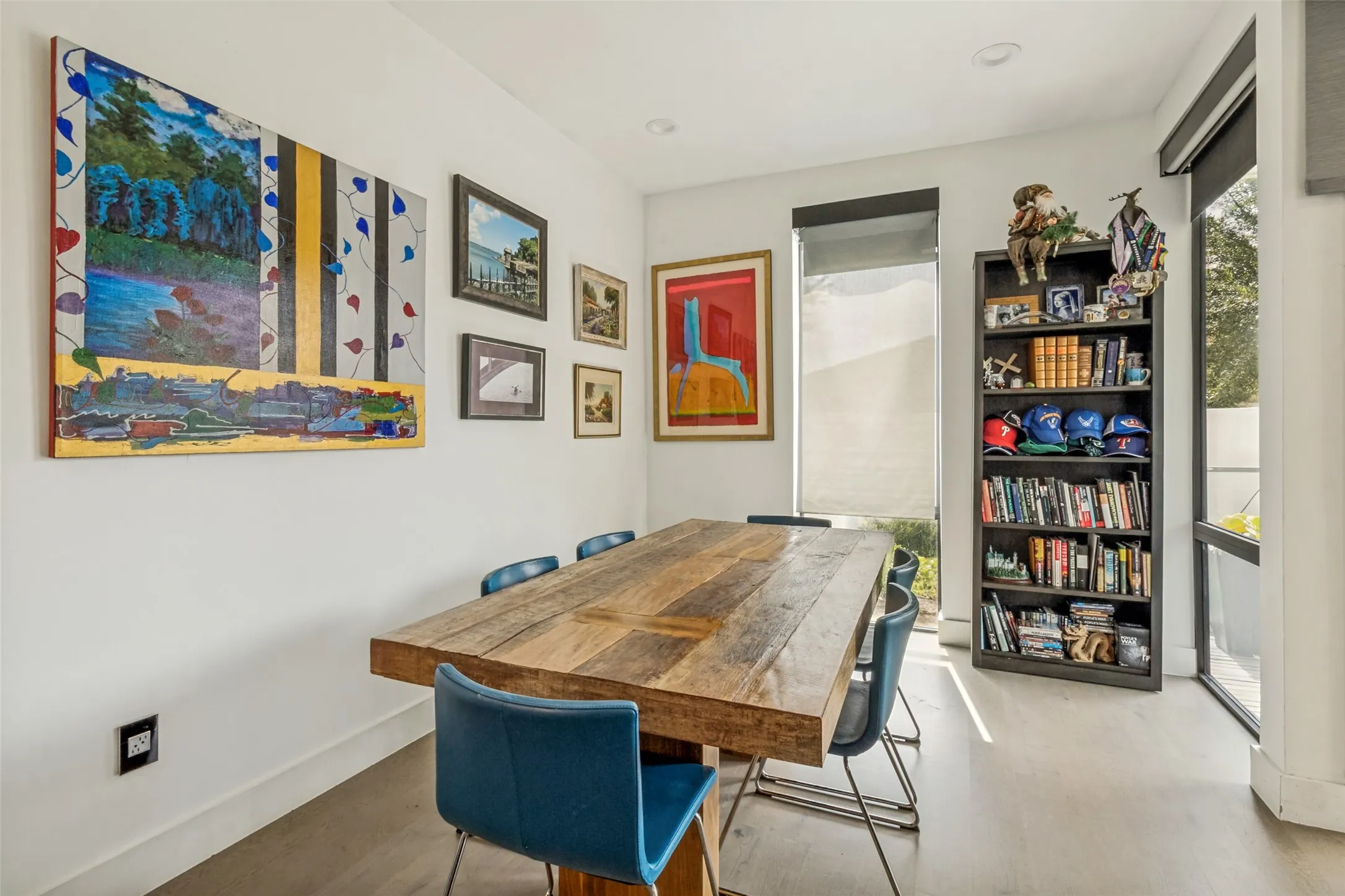 Recessed lighting illuminates the space, featuring wood-finish flooring, white walls, and a built-in dark wood bookcase