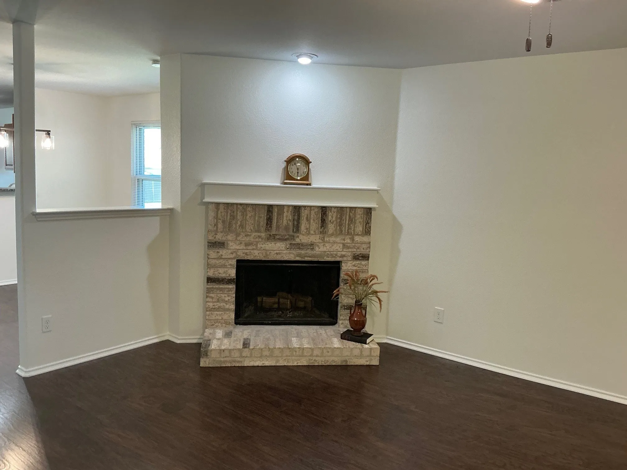 Living room has plank flooring, ceiling fan and fireplace