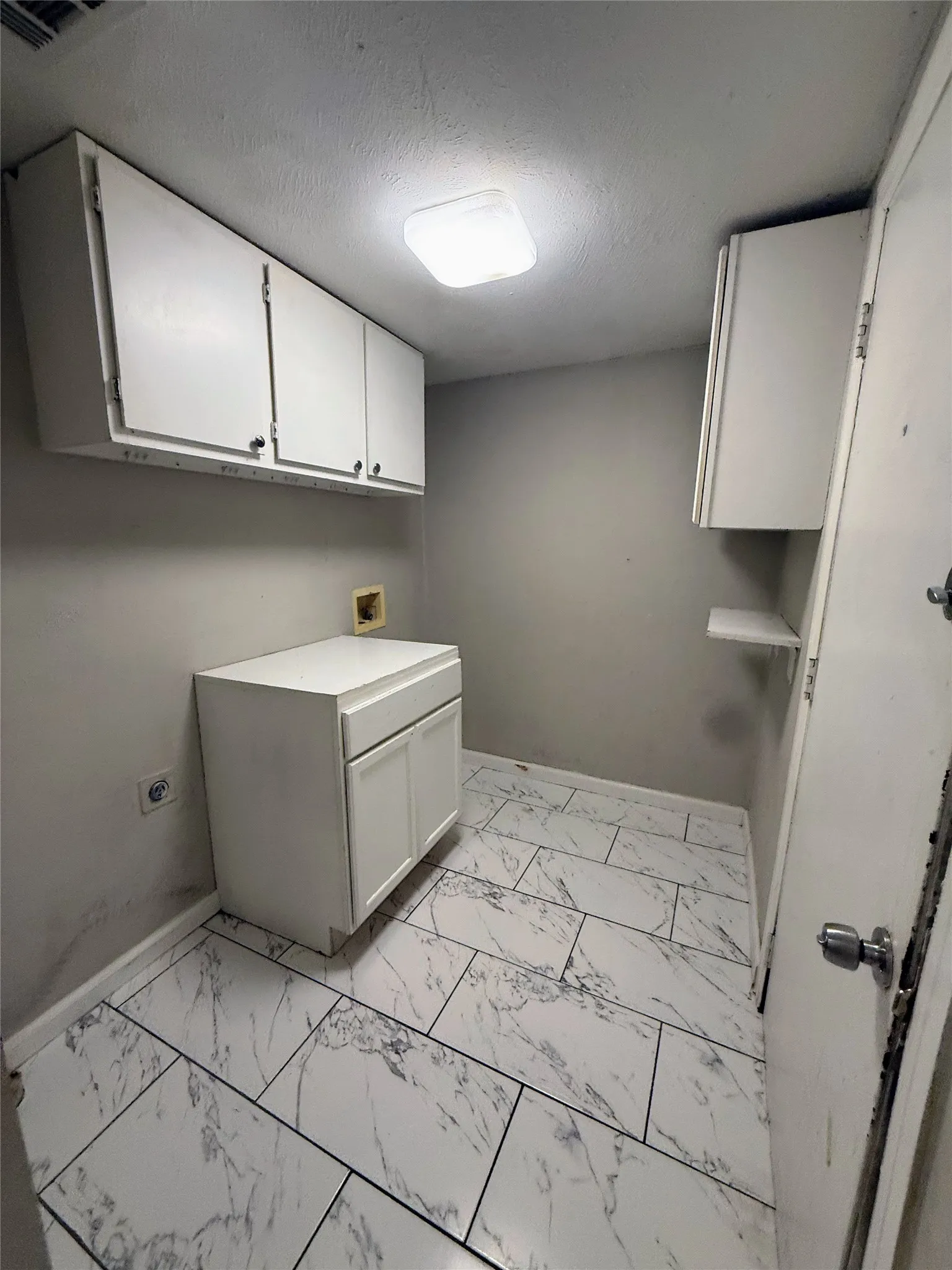 Utility room featuring white shaker-style cabinetry, a built-in base cabinet with countertop, and modern rectangular tile flooring