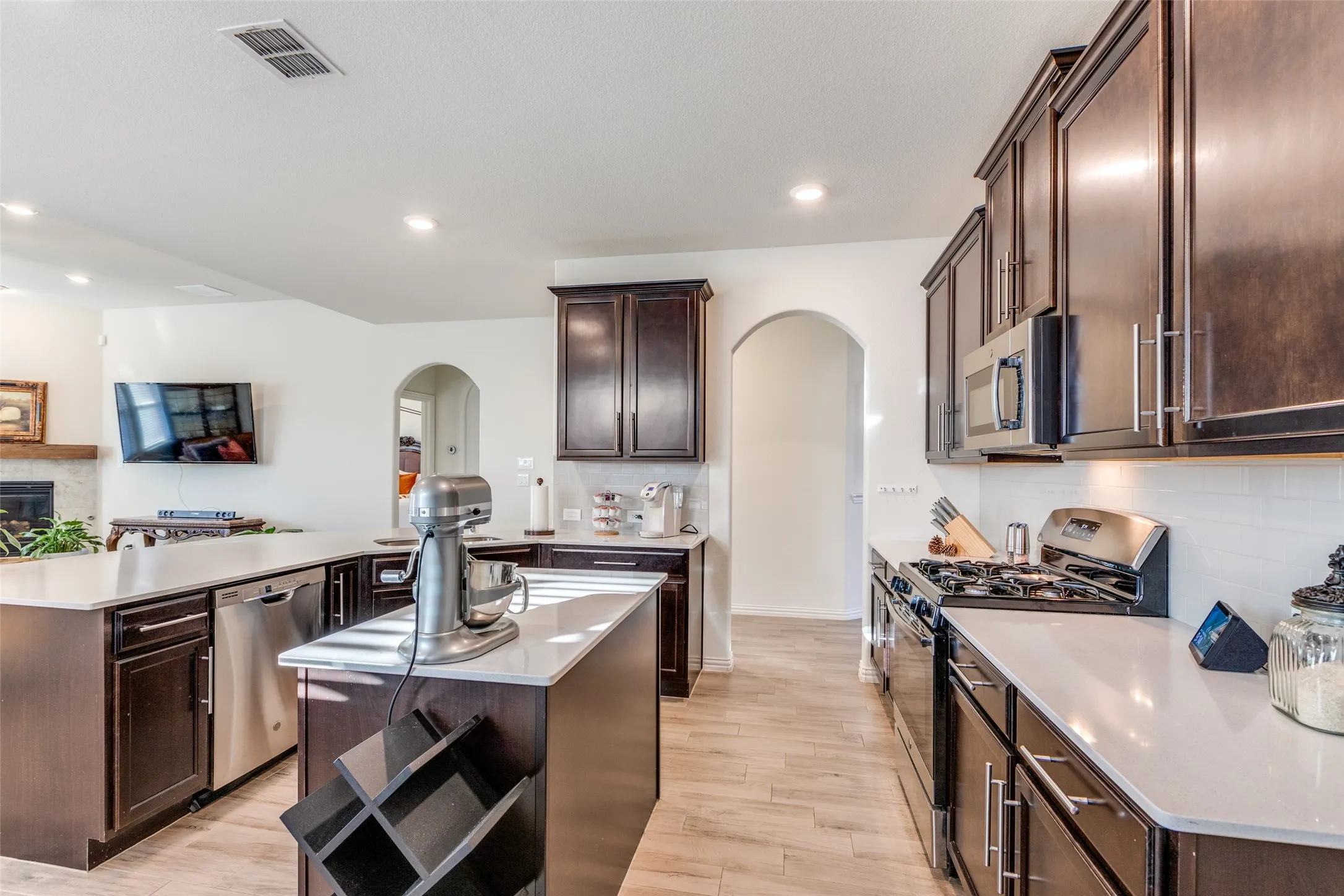 Kitchen featuring decorative backsplash, stainless steel appliances, a center island, dark brown cabinetry, and light hardwood / wood-style floors