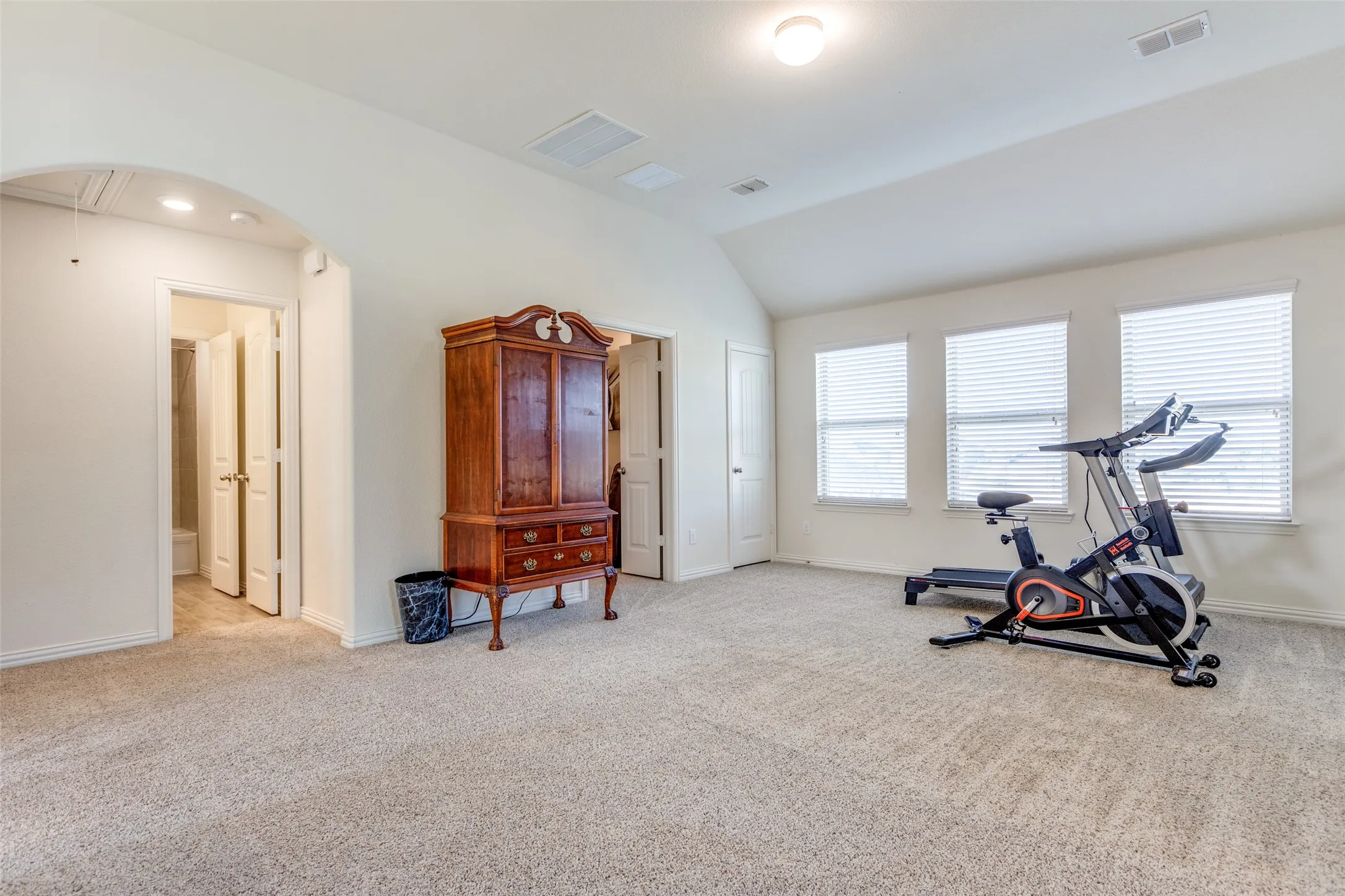 Exercise room featuring light carpet and vaulted ceiling