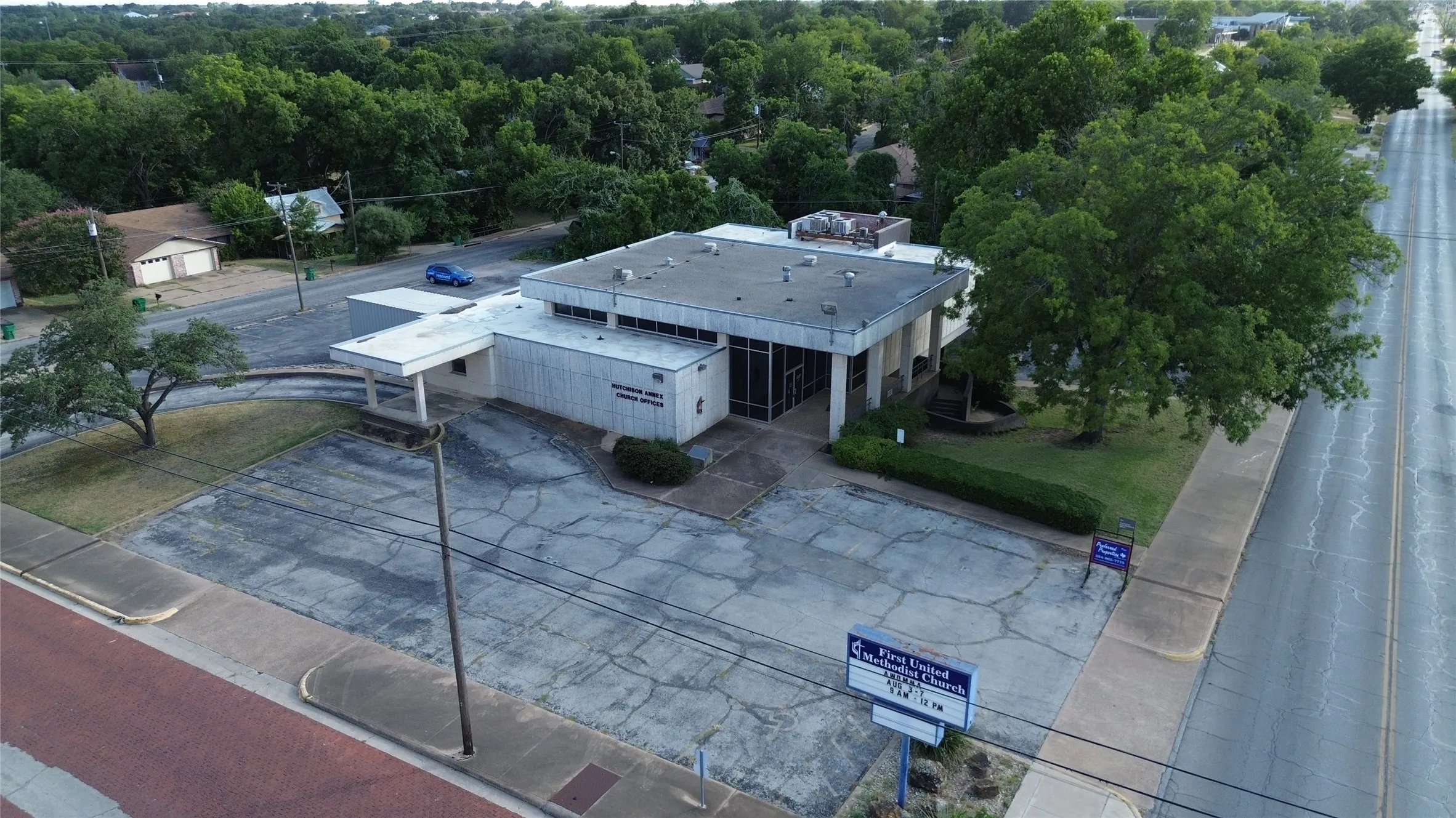 Single-story commercial building with an expansive paved lot and a covered drive-through entrance