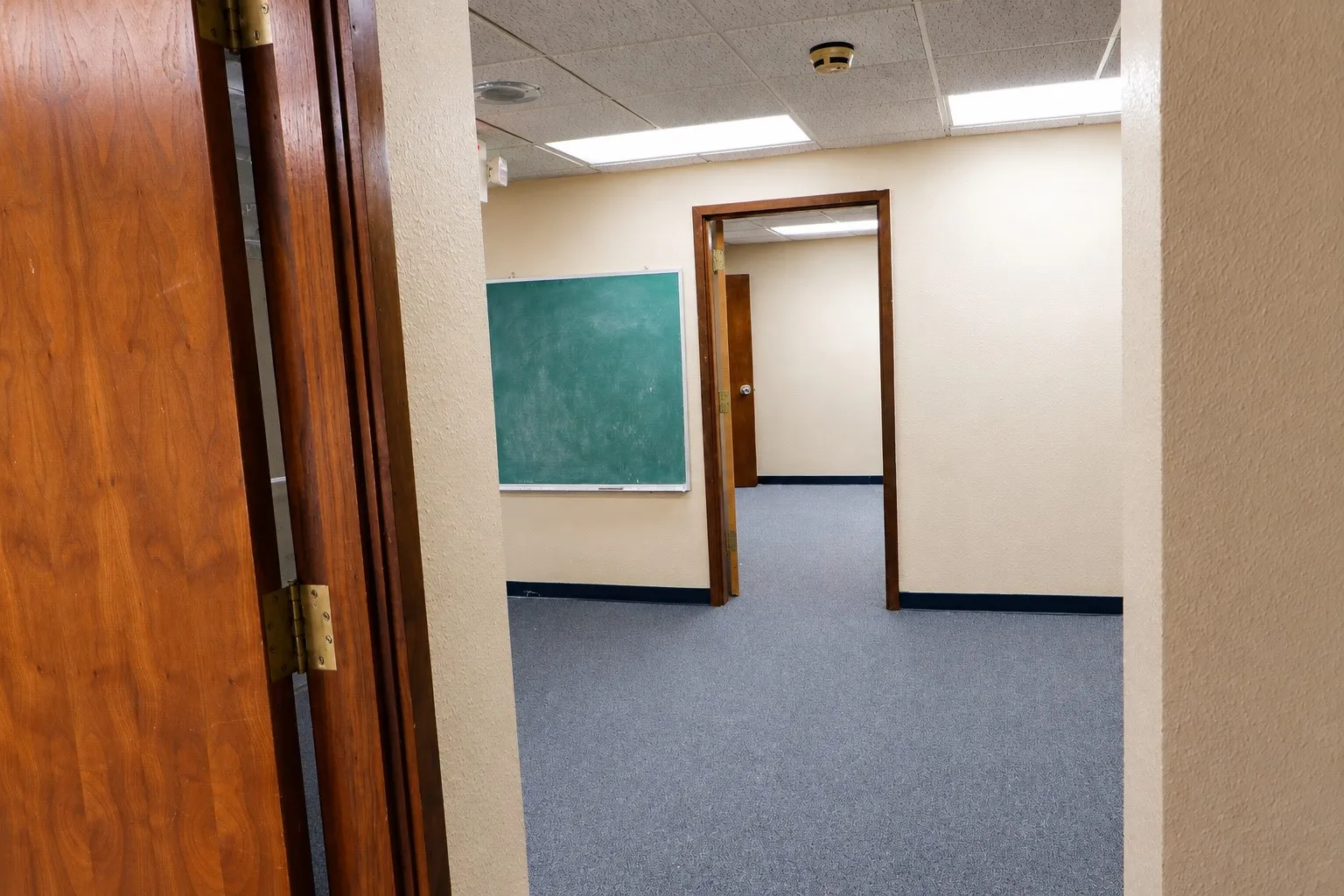 Carpeted flooring, wood-framed doorways, and a mounted chalkboard