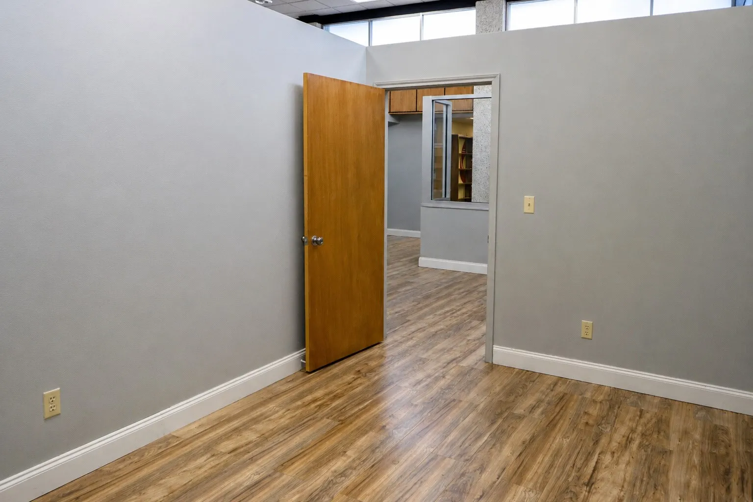 Wood-finish flooring with white baseboards and light gray walls