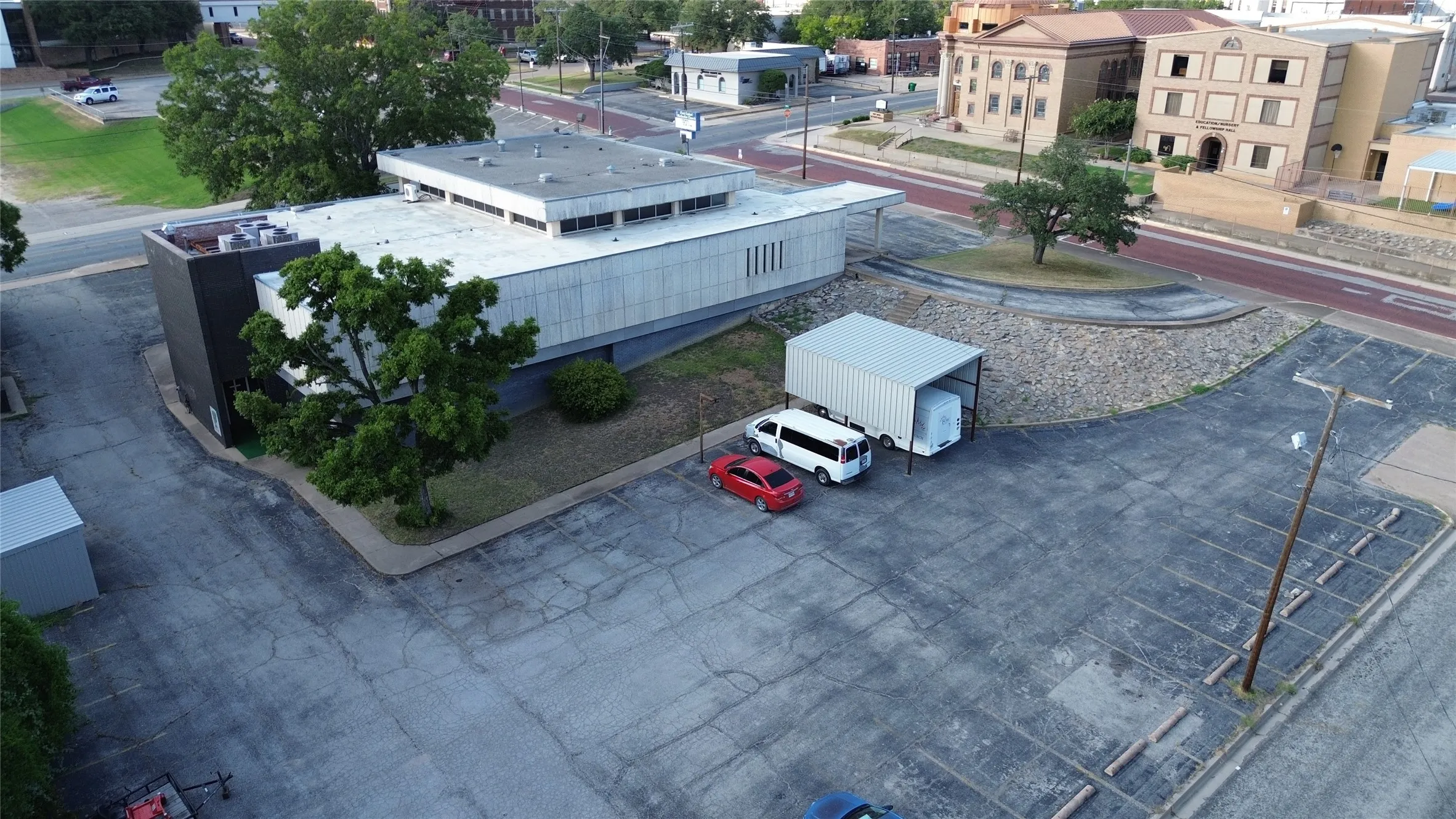 Expansive paved parking lot with designated spaces, featuring a metal car shelter