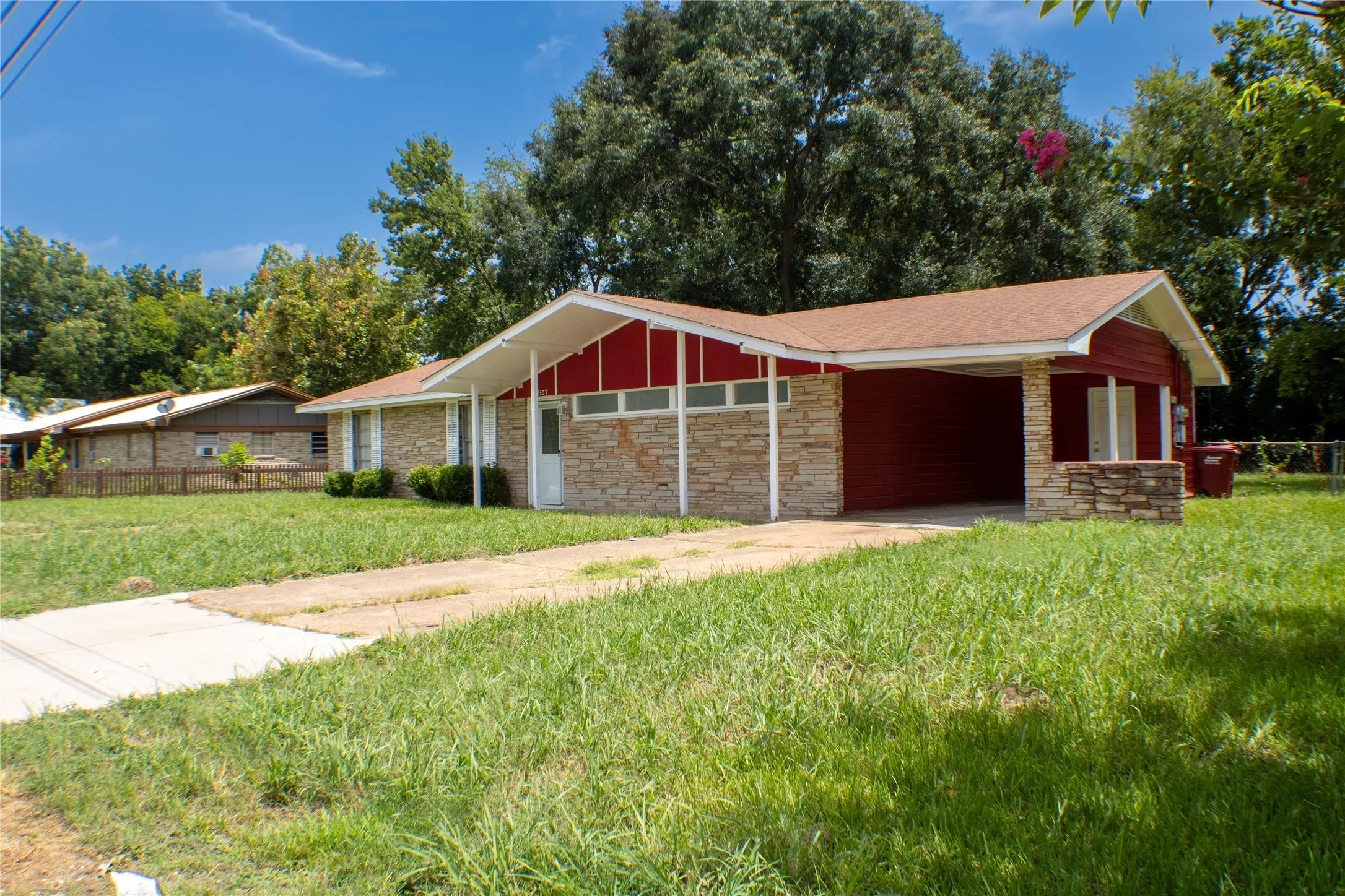 Ranch-style residence featuring stone veneer and red siding