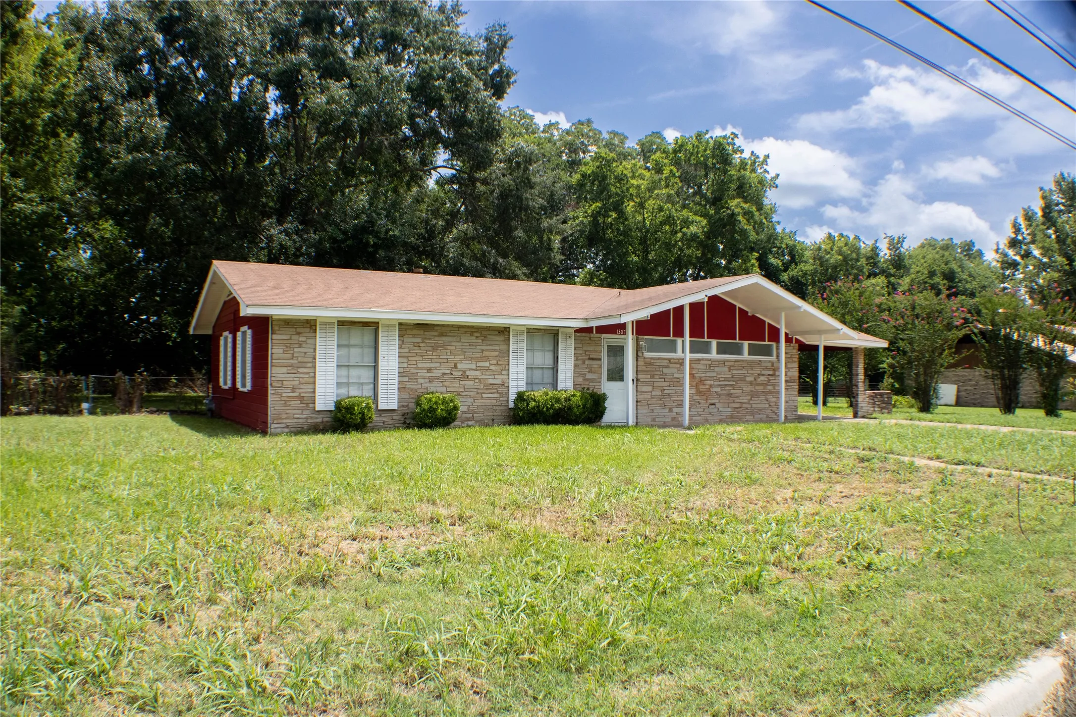 Stone and red siding exterior with white window shutters