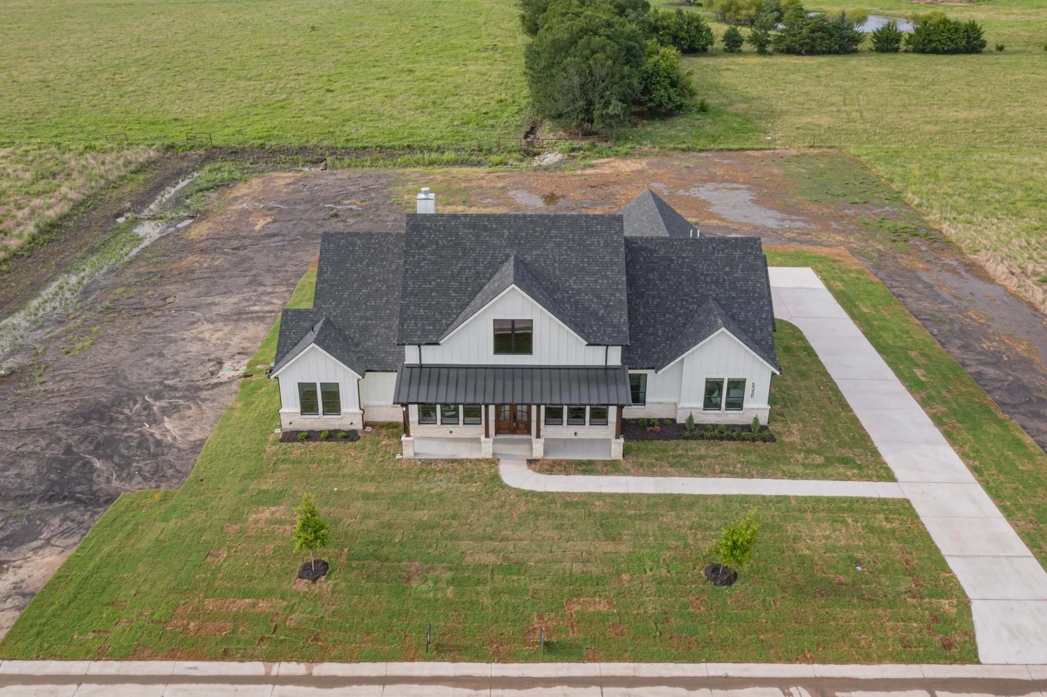 White board-and-batten exterior with a dark shingle roof and a prominent metal accent roof over the entry